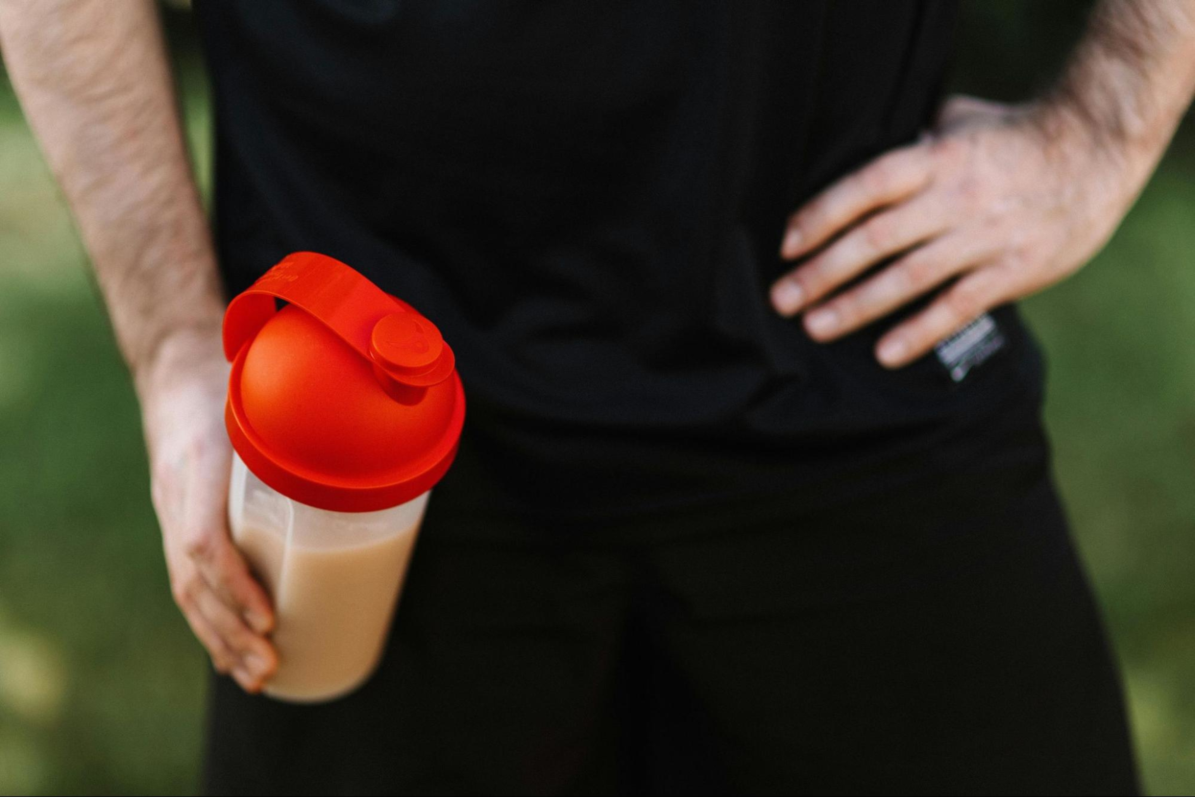 Man holds a bottle with a protein shake after a workout to build muscle with protein.