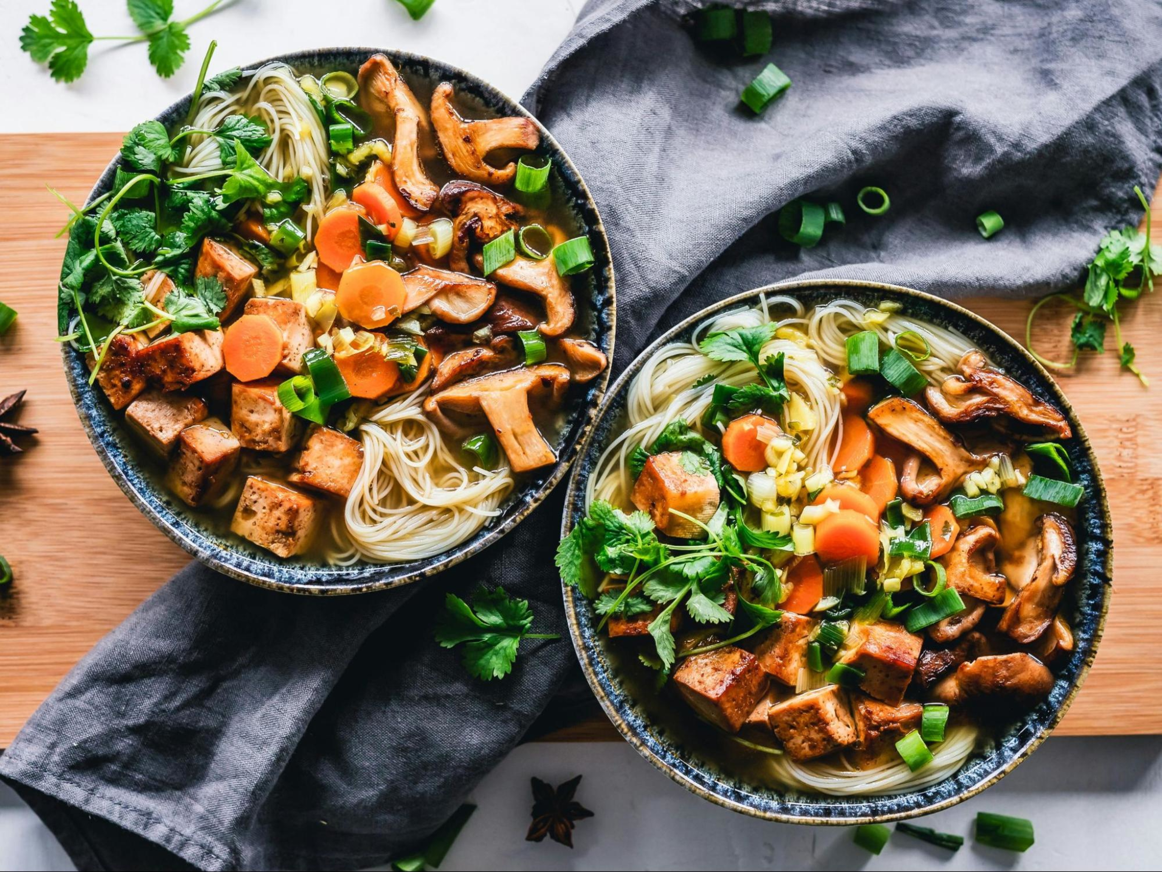 Two noodle bowls with tofu, a good option for those learning how much protein they need for muscle growth.