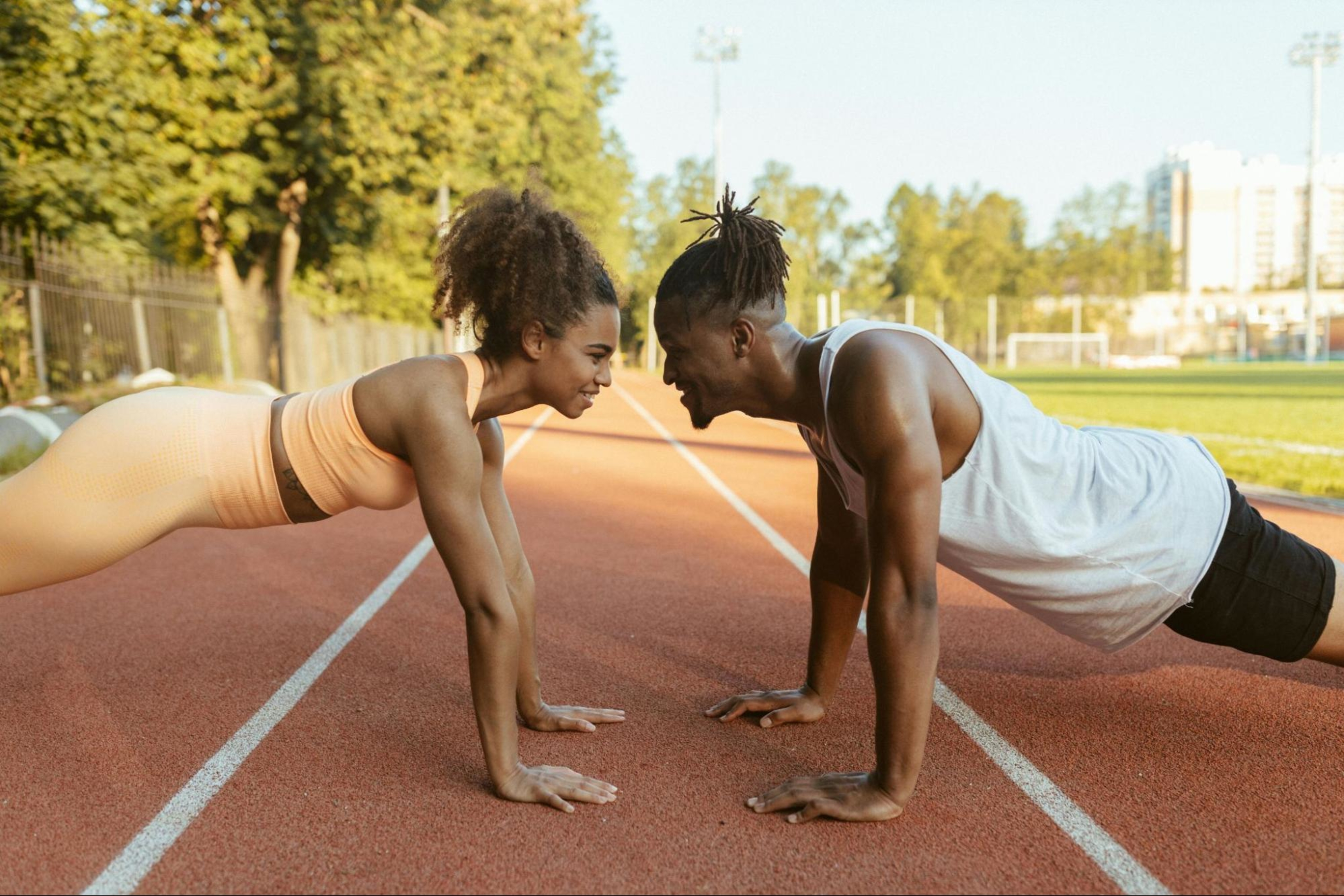 Couple does plank exercise together after deciding between split training vs. full-body training.