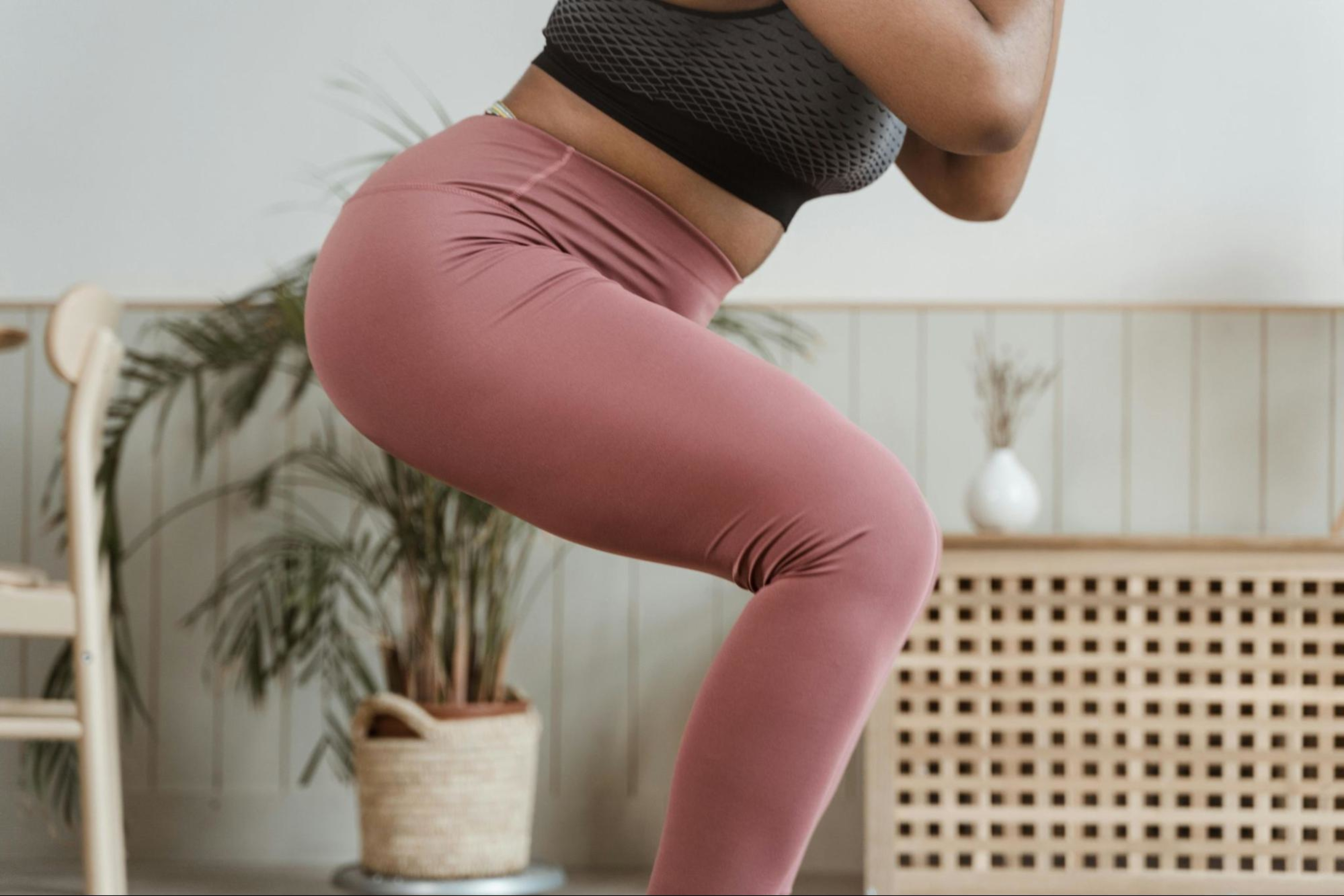 Woman does a squat as part of a postpartum strength training plan.
