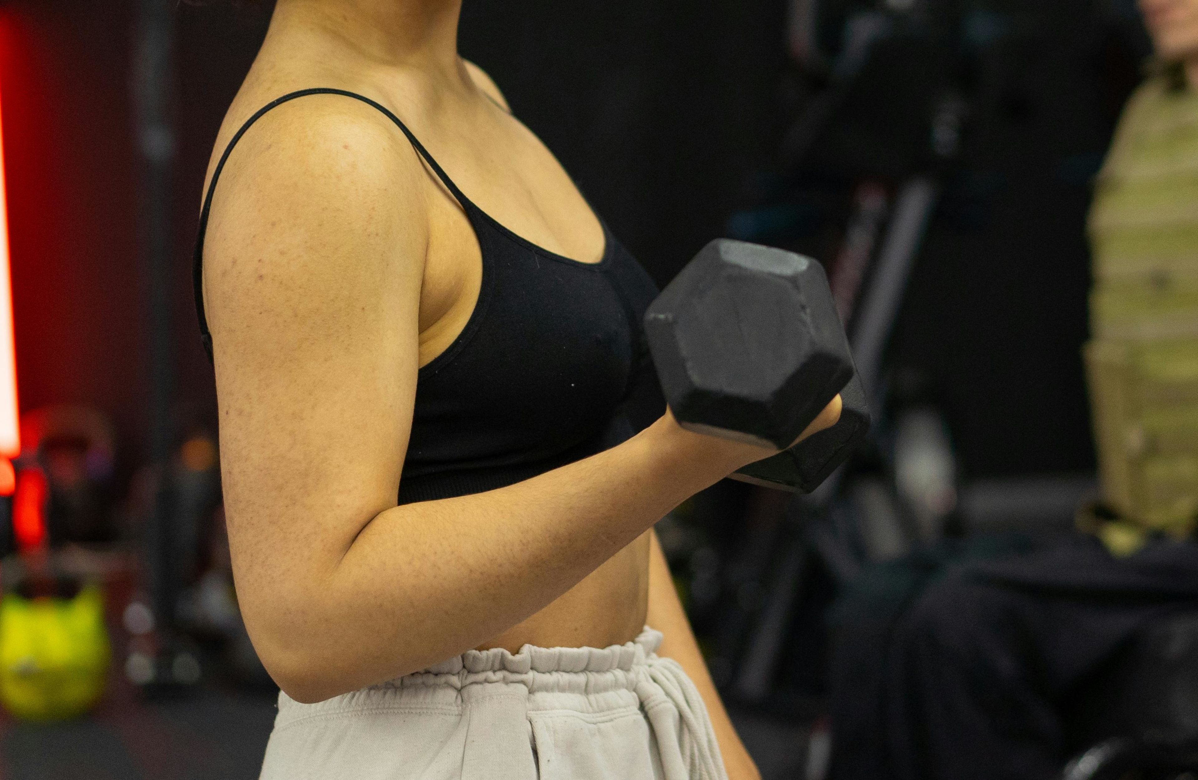 Woman lifts a dumbbell while strength training postpartum.