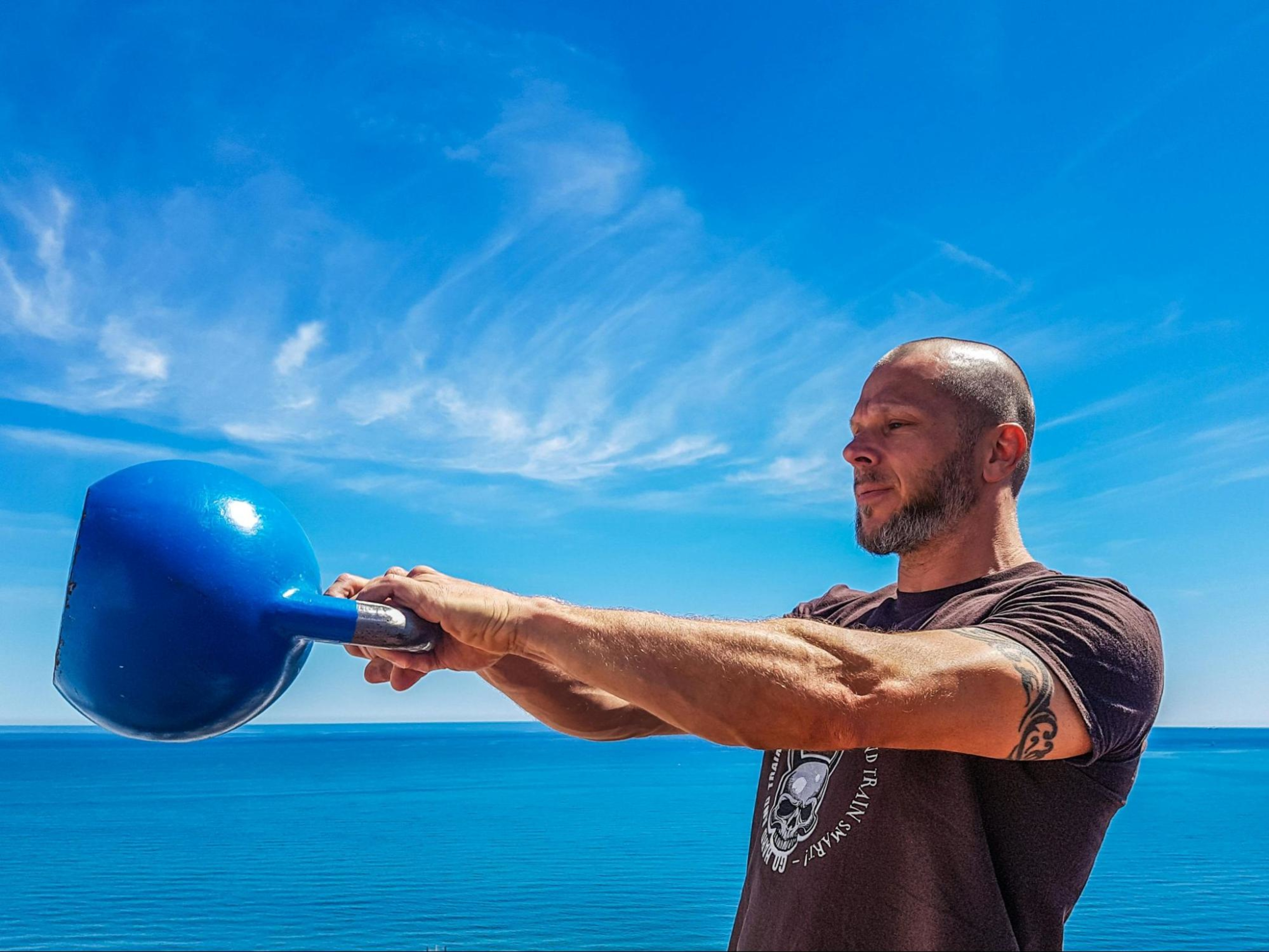 Man works out with a kettlebell outdoors to train for a marathon.