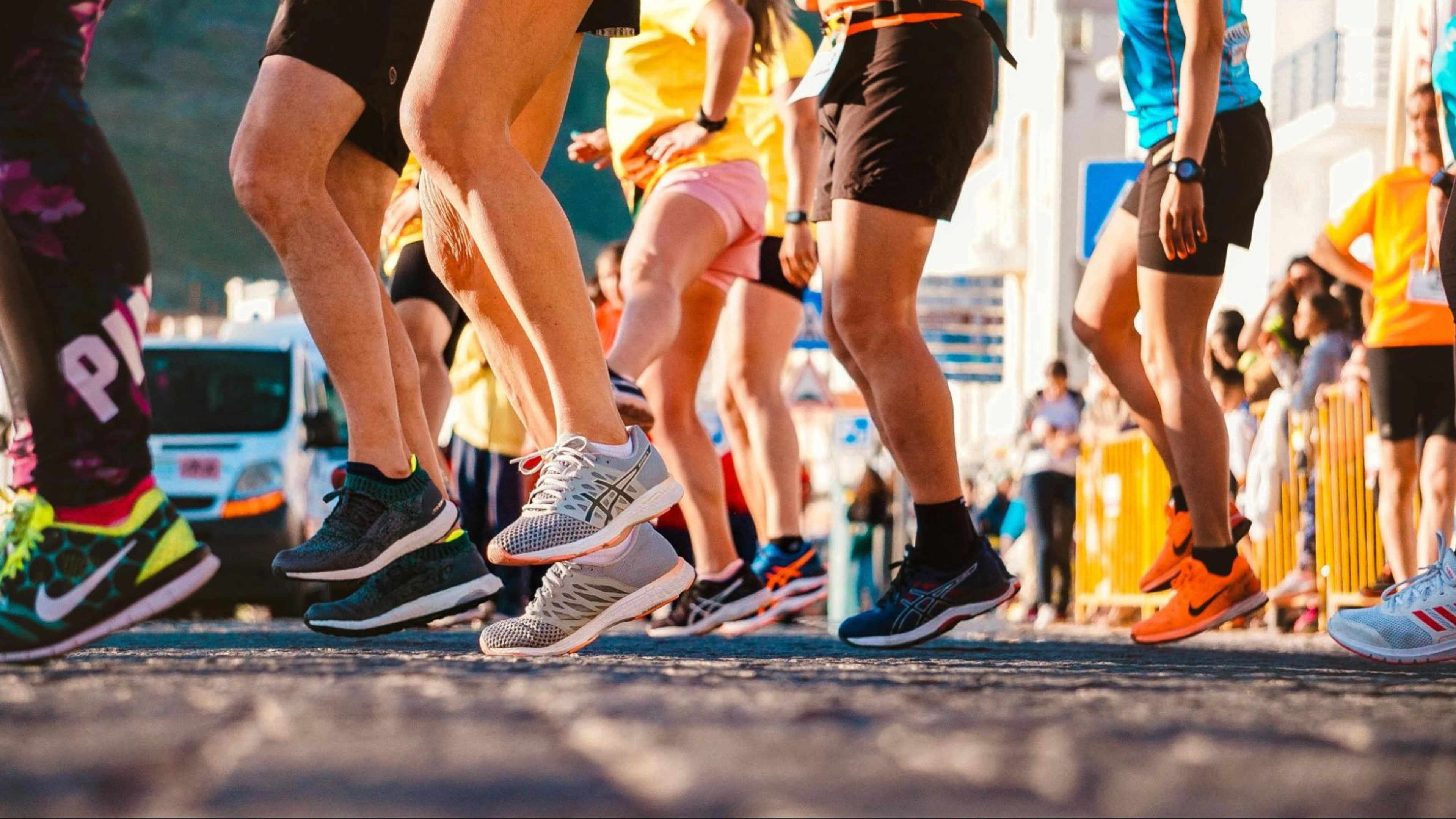A group of people wearing sneakers prepare to run a marathon.
