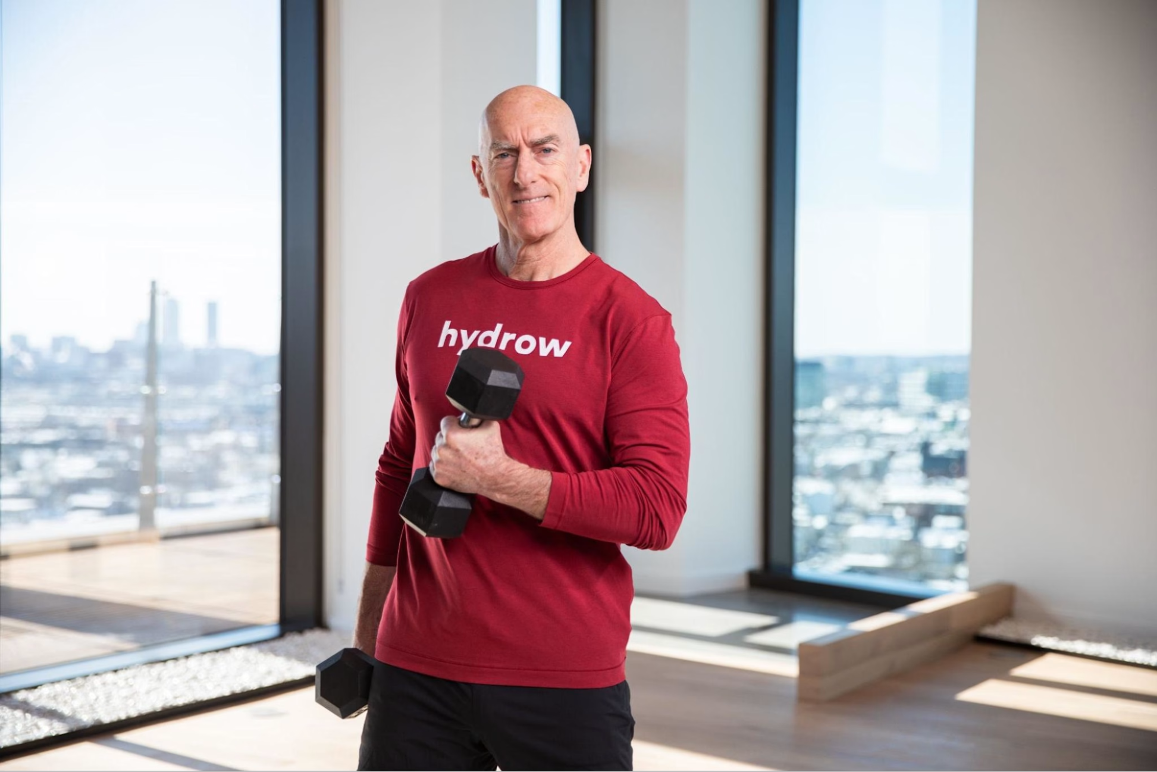Hydrow Athlete Pete leads a strength training workout for marathon training with a dumbbell in hand.