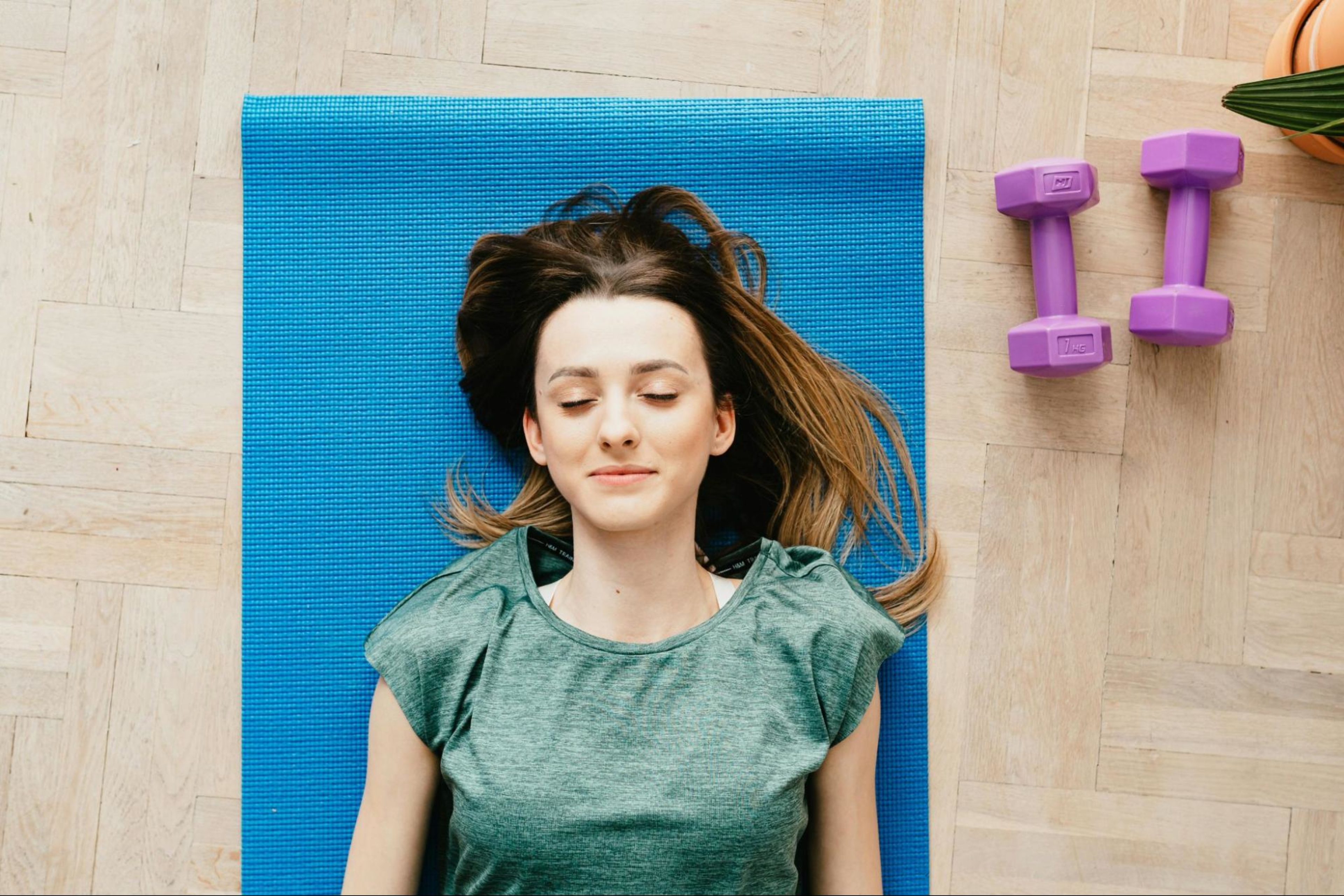 Pregnant woman lays down on a yoga mat while doing a pregnancy strength training program.
