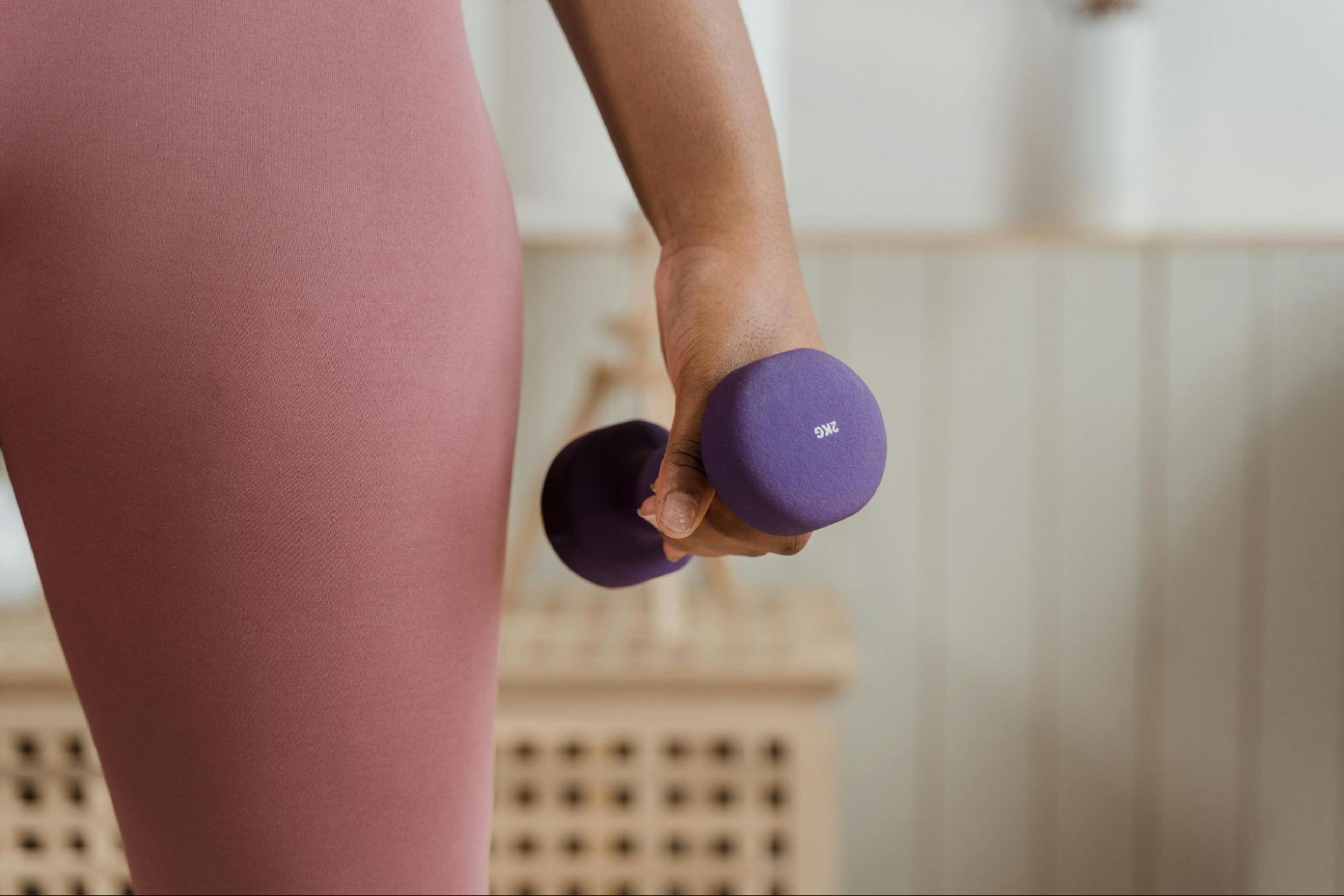 Woman holding a purple dumbbell follows tips for strength training during pregnancy.