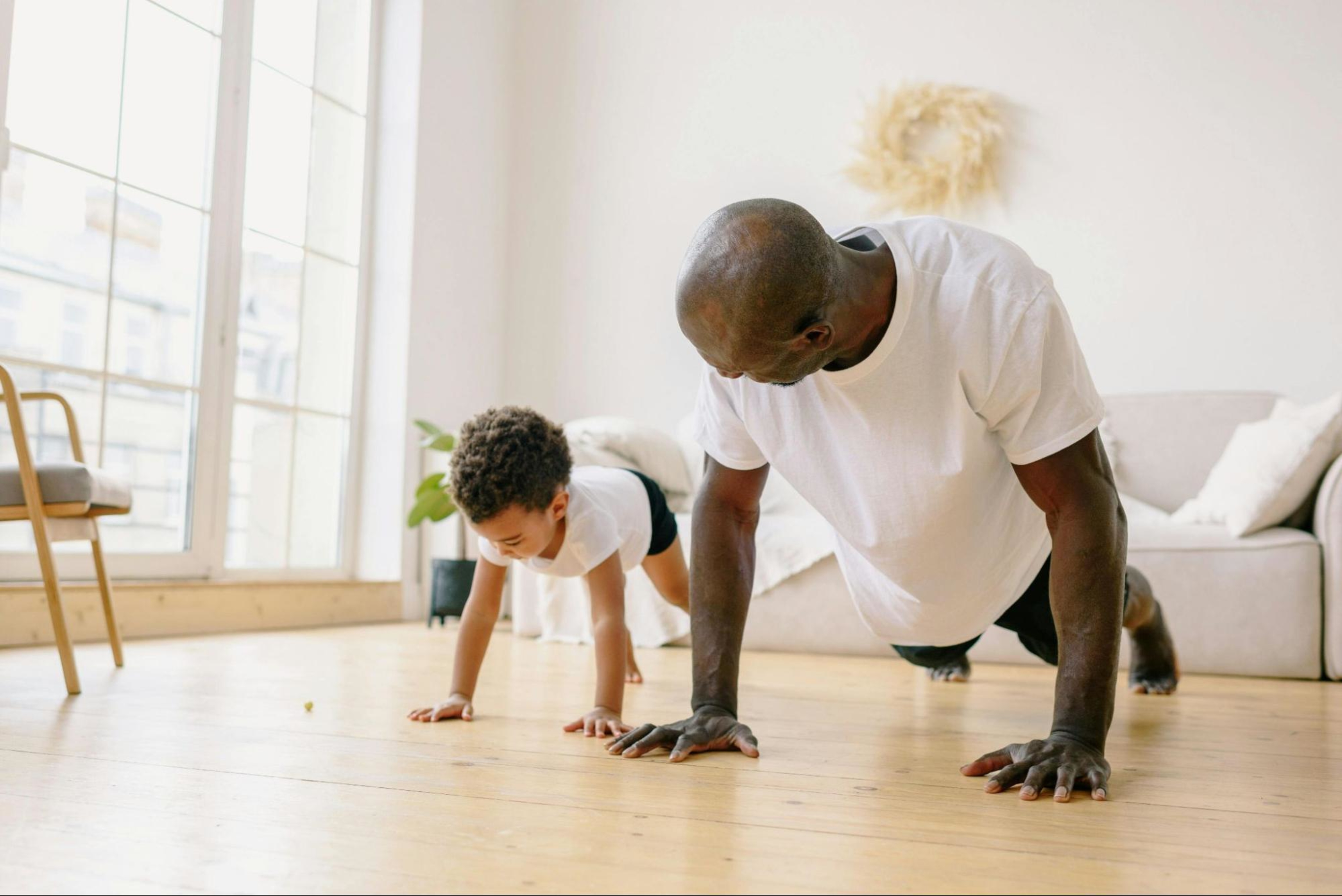 Man follows tips for starting strength training in your 40s while doing a plank alongside his son.