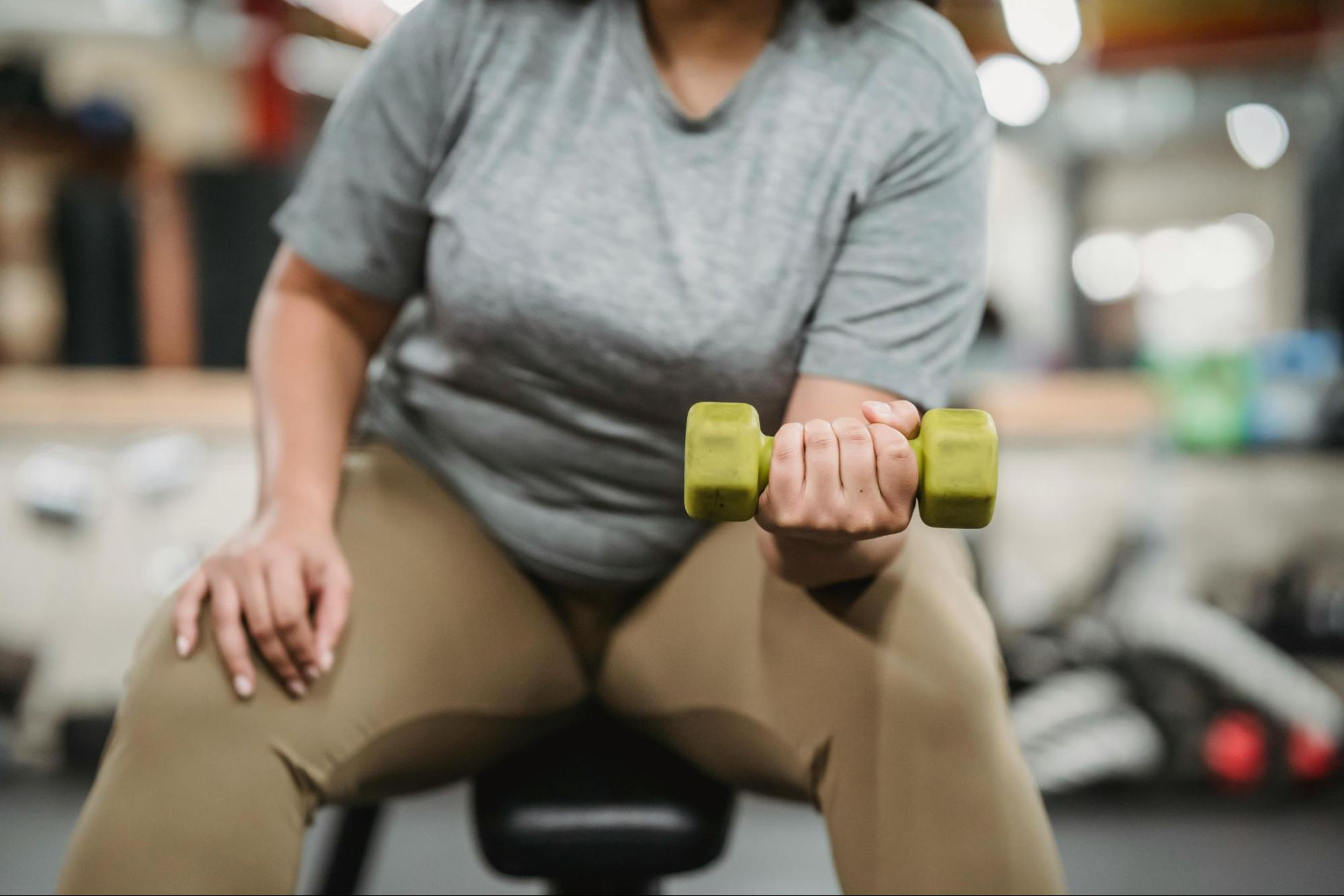 Woman in a gym holding a green dumbbell follows tips for strength training in your 40s.