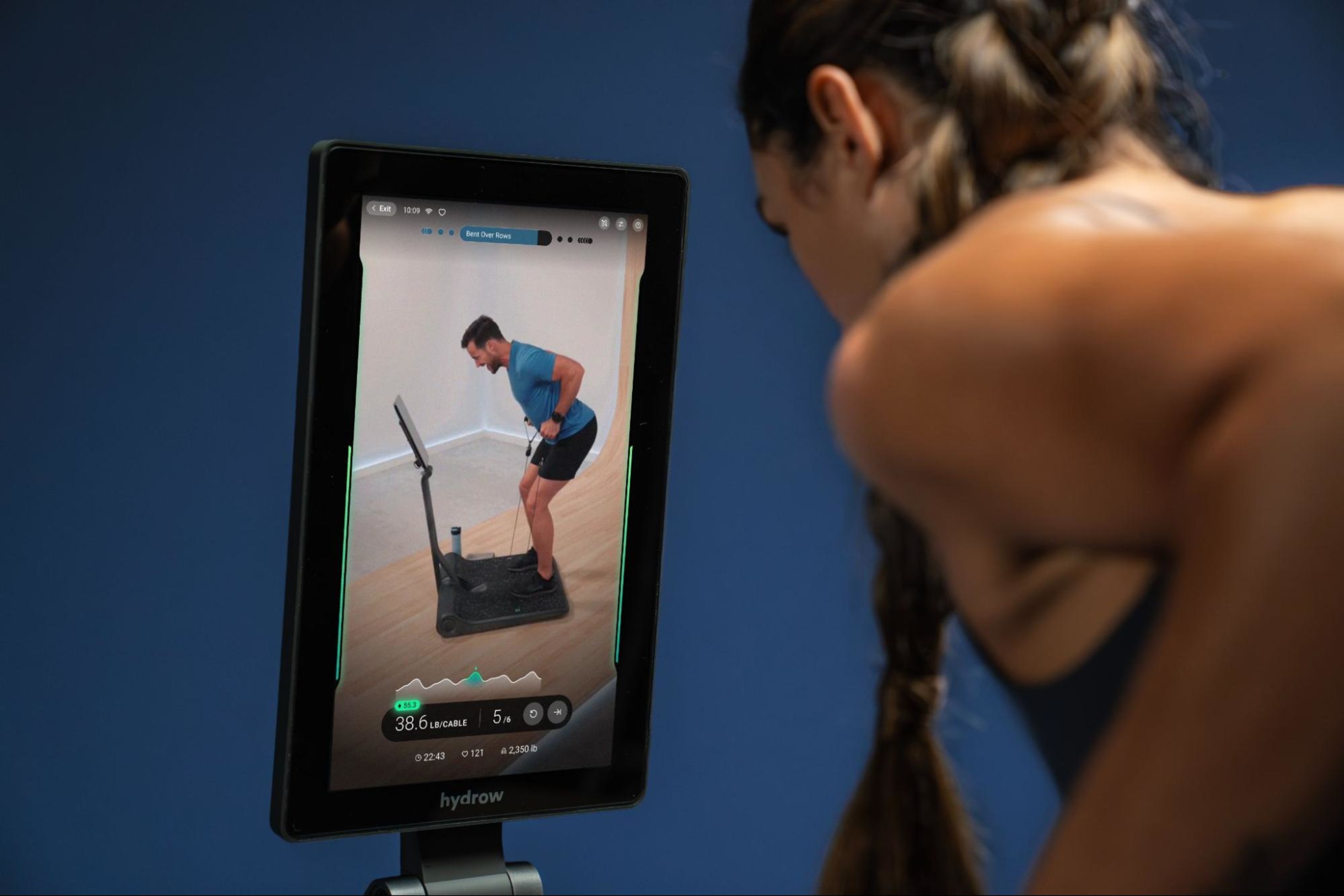 Woman does a workout on a LYQUID strength machine led by Lance.
