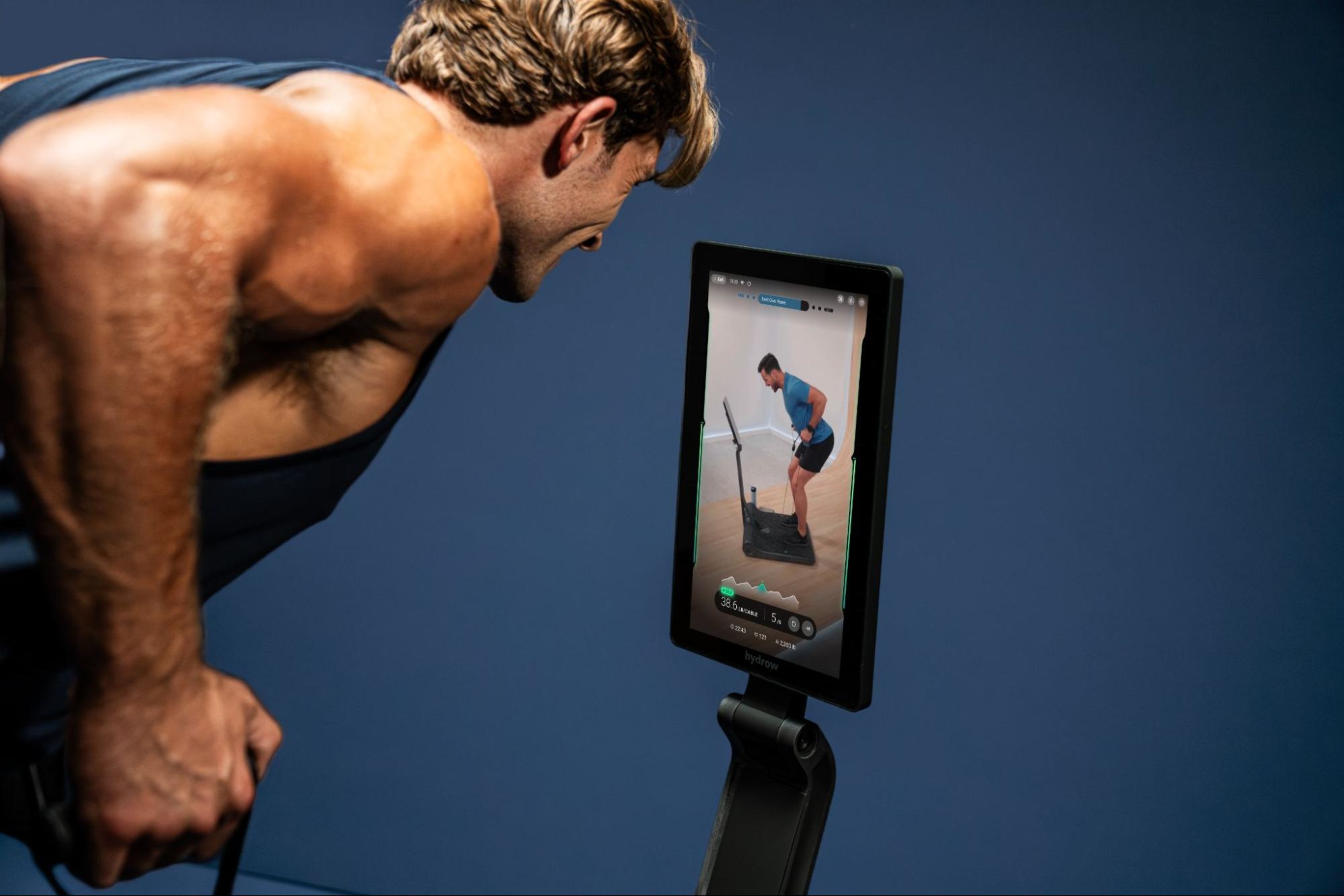 A man does a workout on his LYQUID strength machine, leveraging his membership for premium workout content.