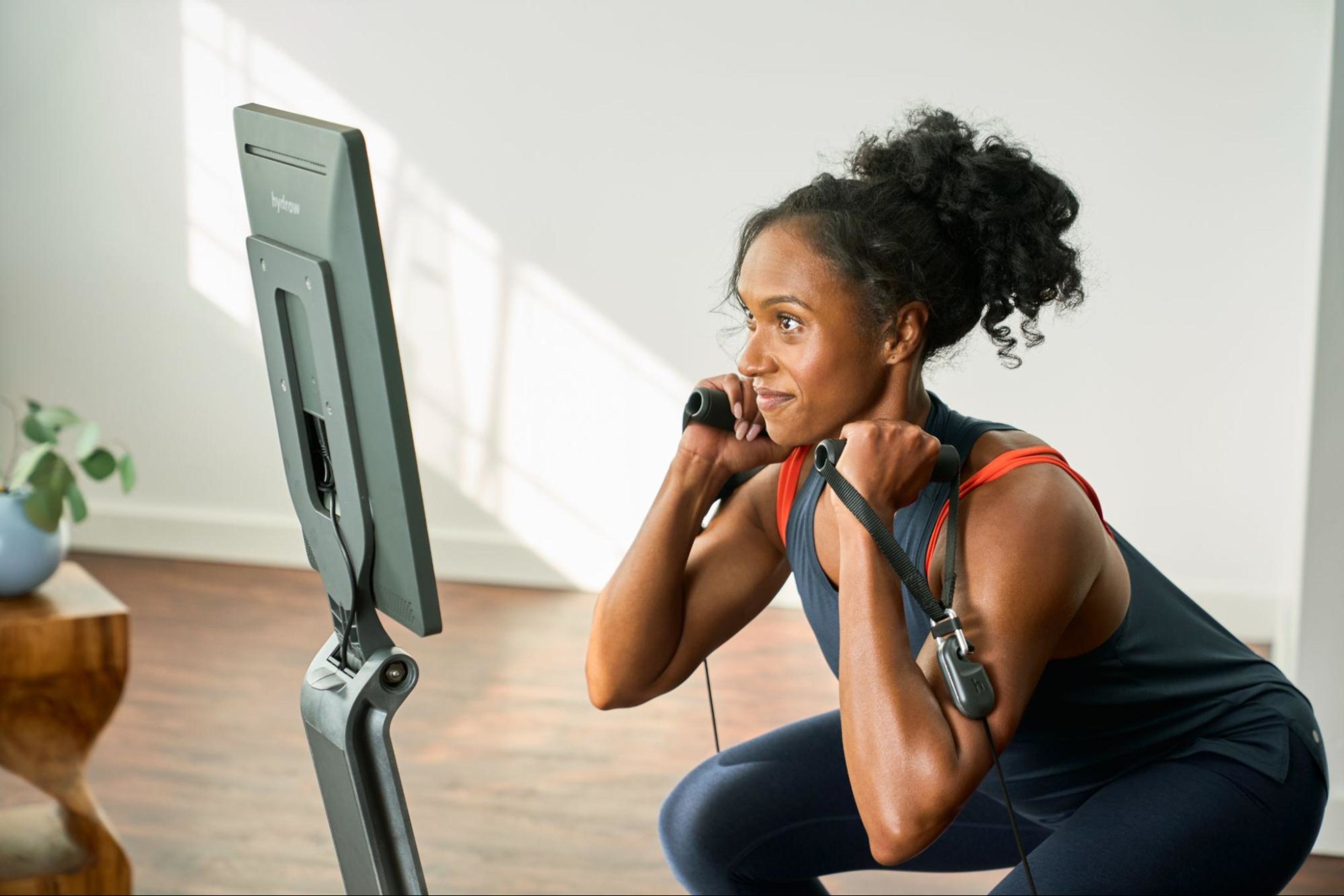 A woman does a workout at home on a LYQUID strength machine.