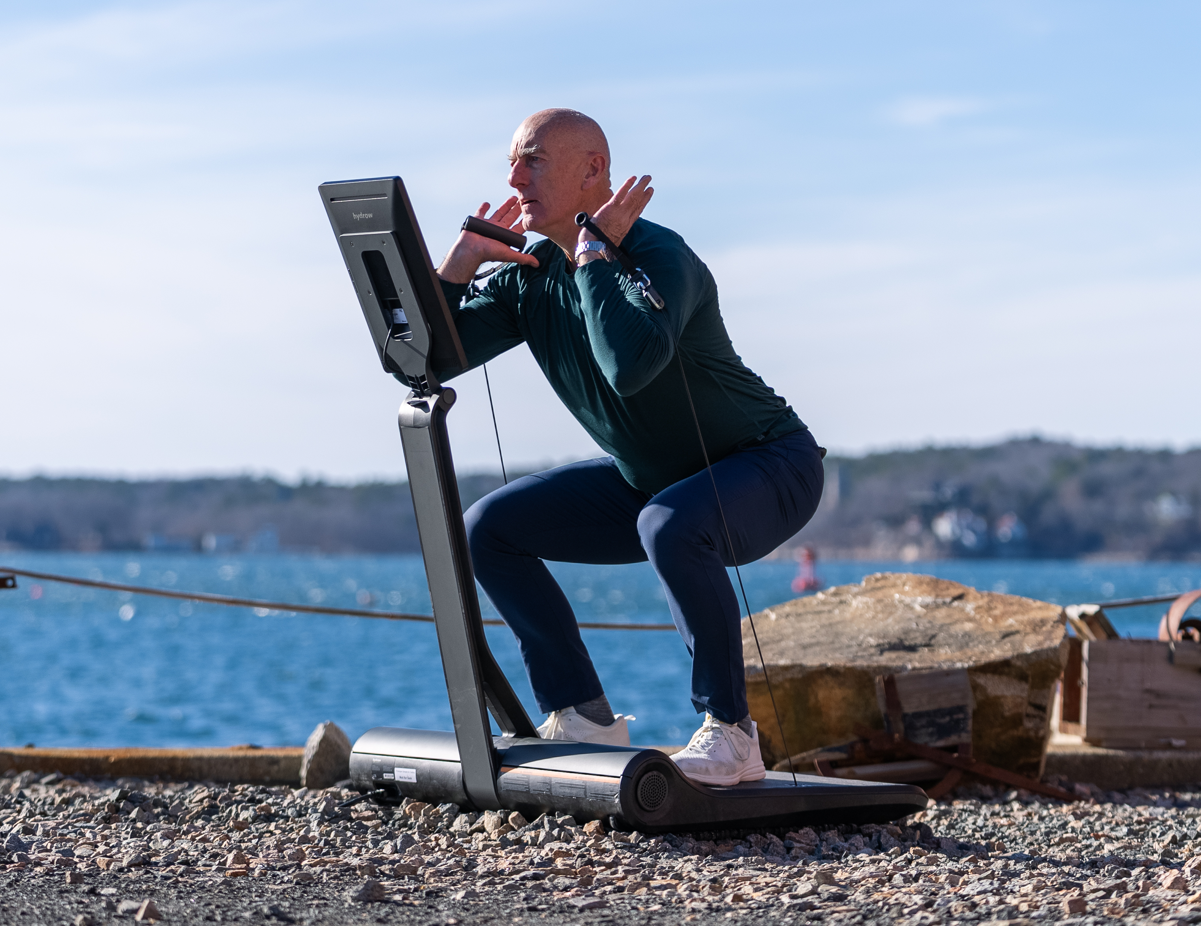 Hydrow Athlete Pete Donohoe does a front rack squat on a LYQUID strength machine outdoors.