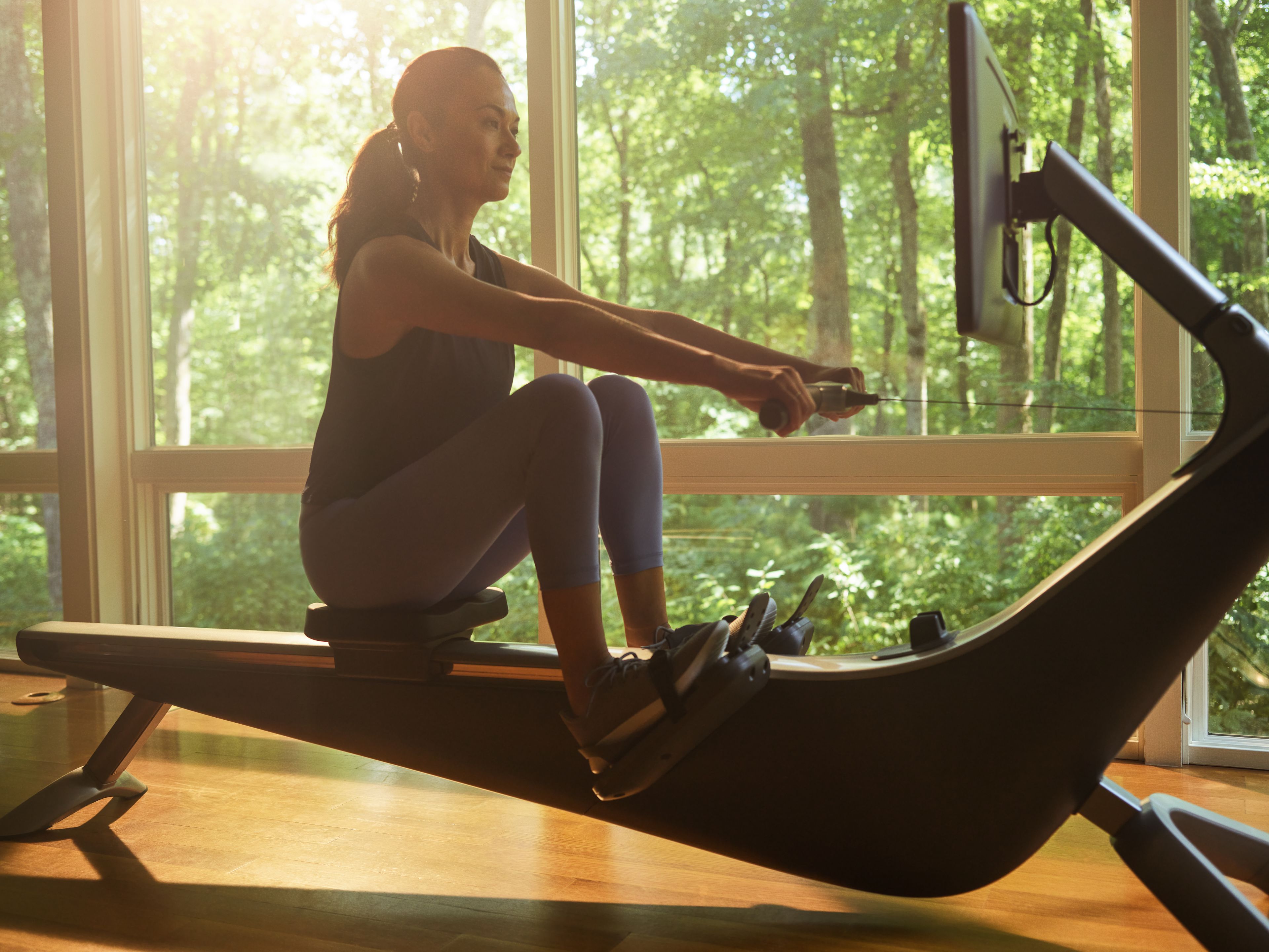 Woman works out on a rowing machine after establishing good exercise habits.