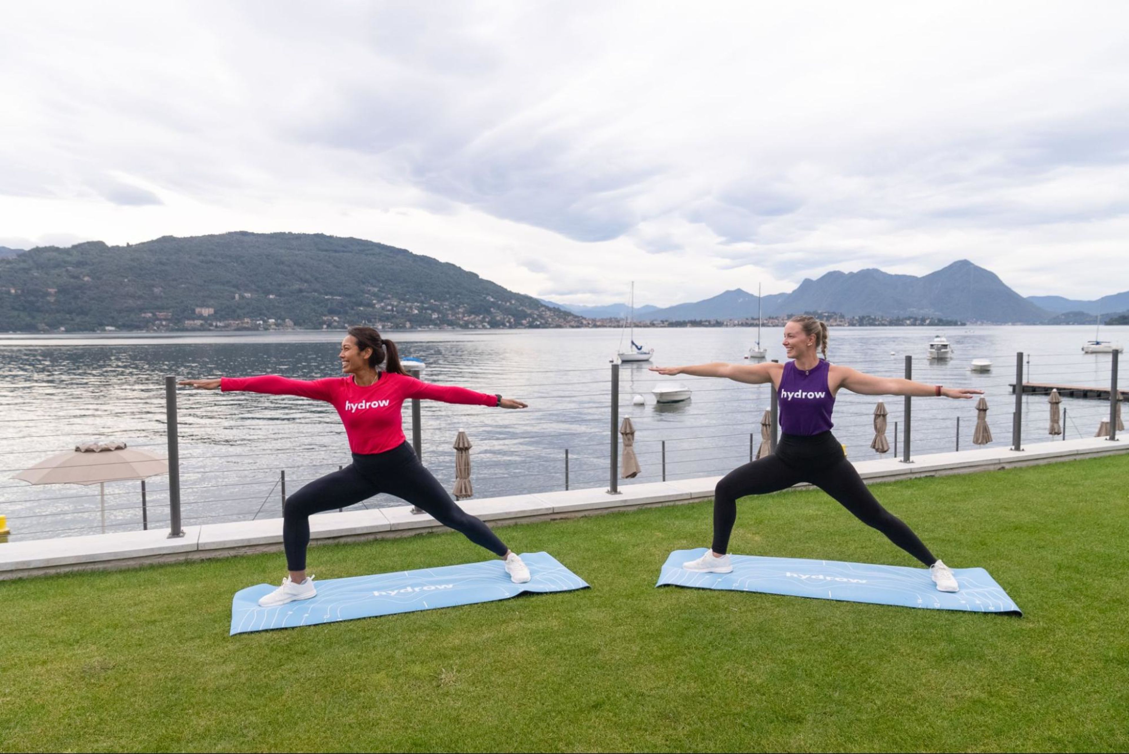 Two women do a yoga workout outdoors to help with back pain.