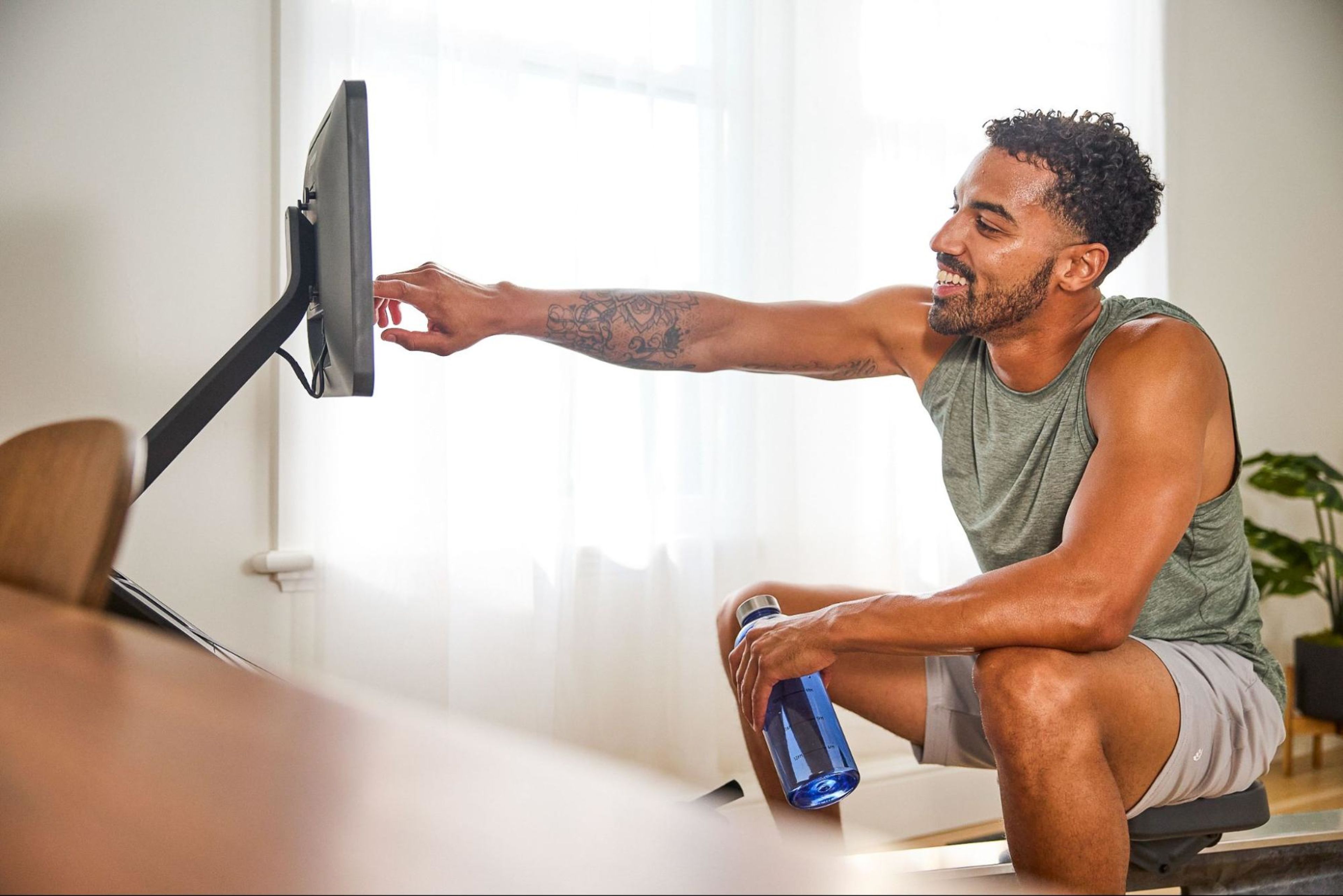 Man prepares to work out on a rowing machine after learning how to do aerobics at home.