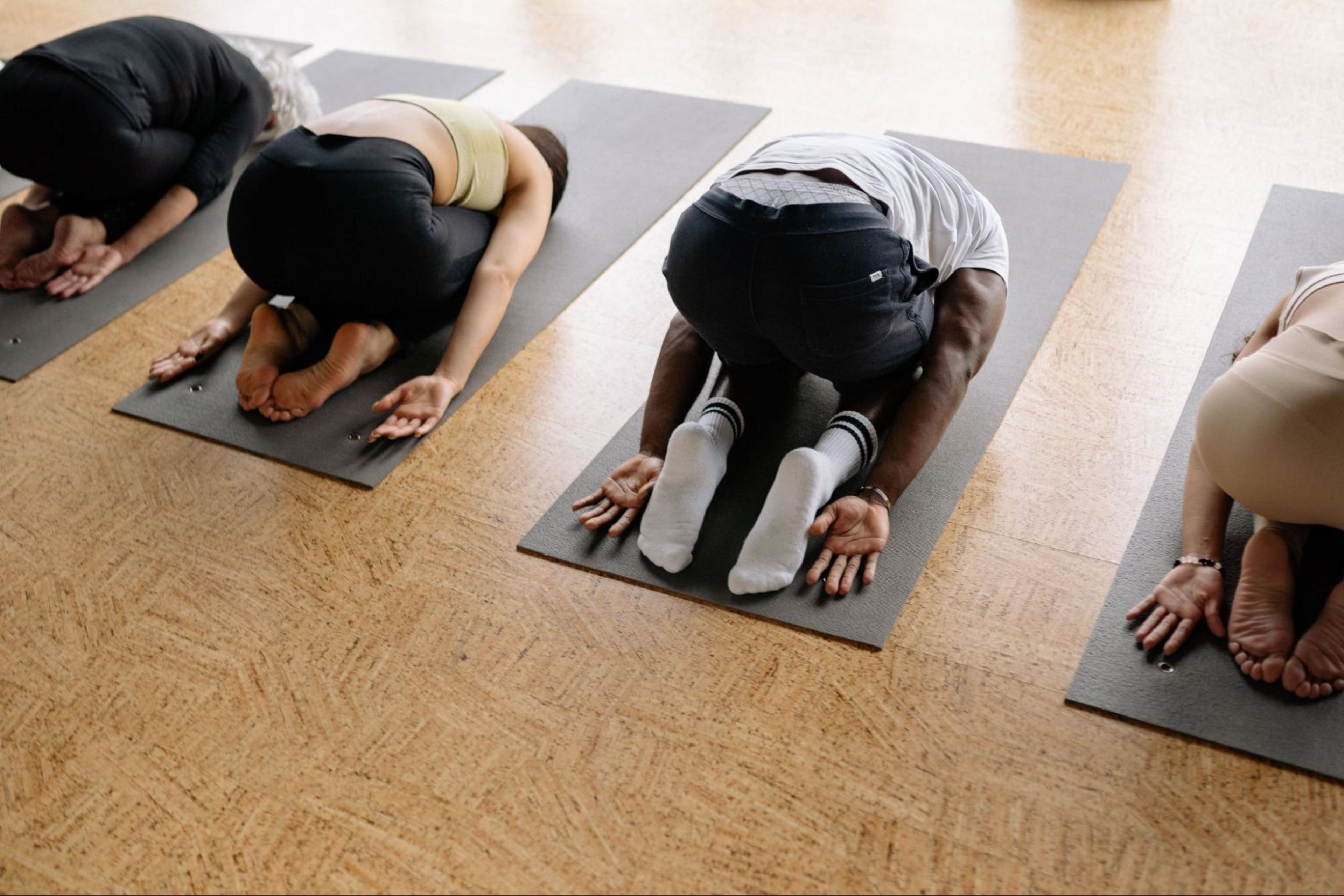 Four people do a restorative yoga workout indoors after learning about what restorative yoga is.