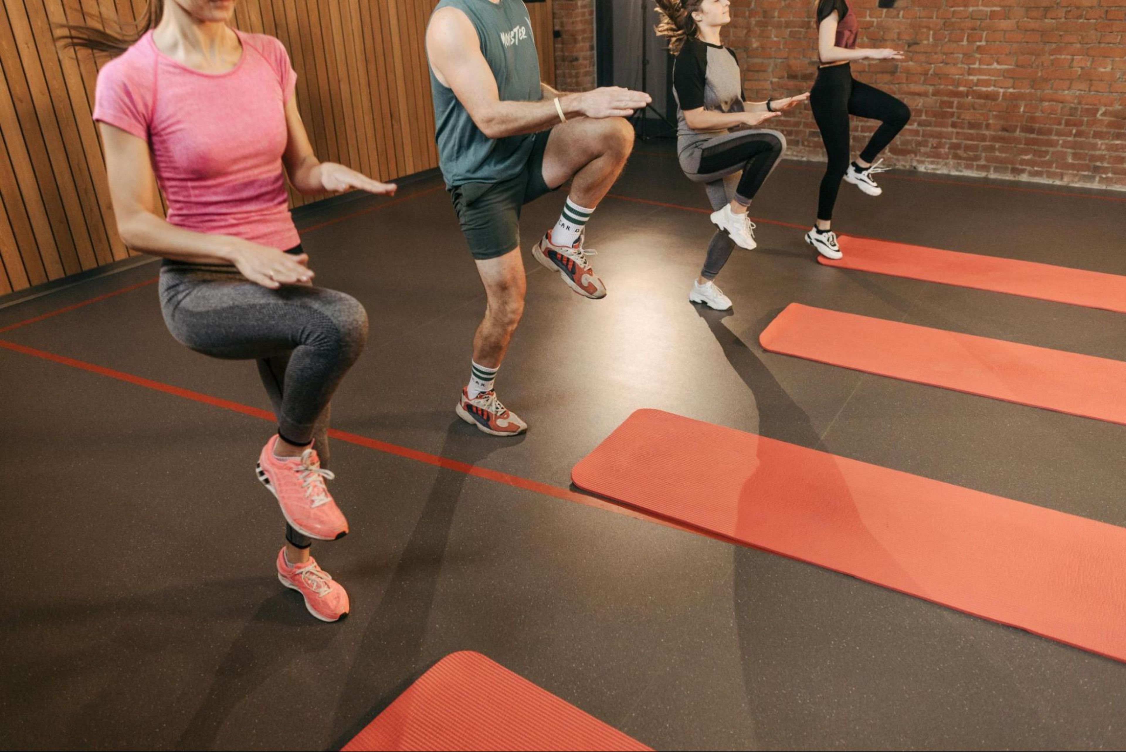 Men and women participate in a group fitness cardio class after learning about what cardio exercise does for the body.