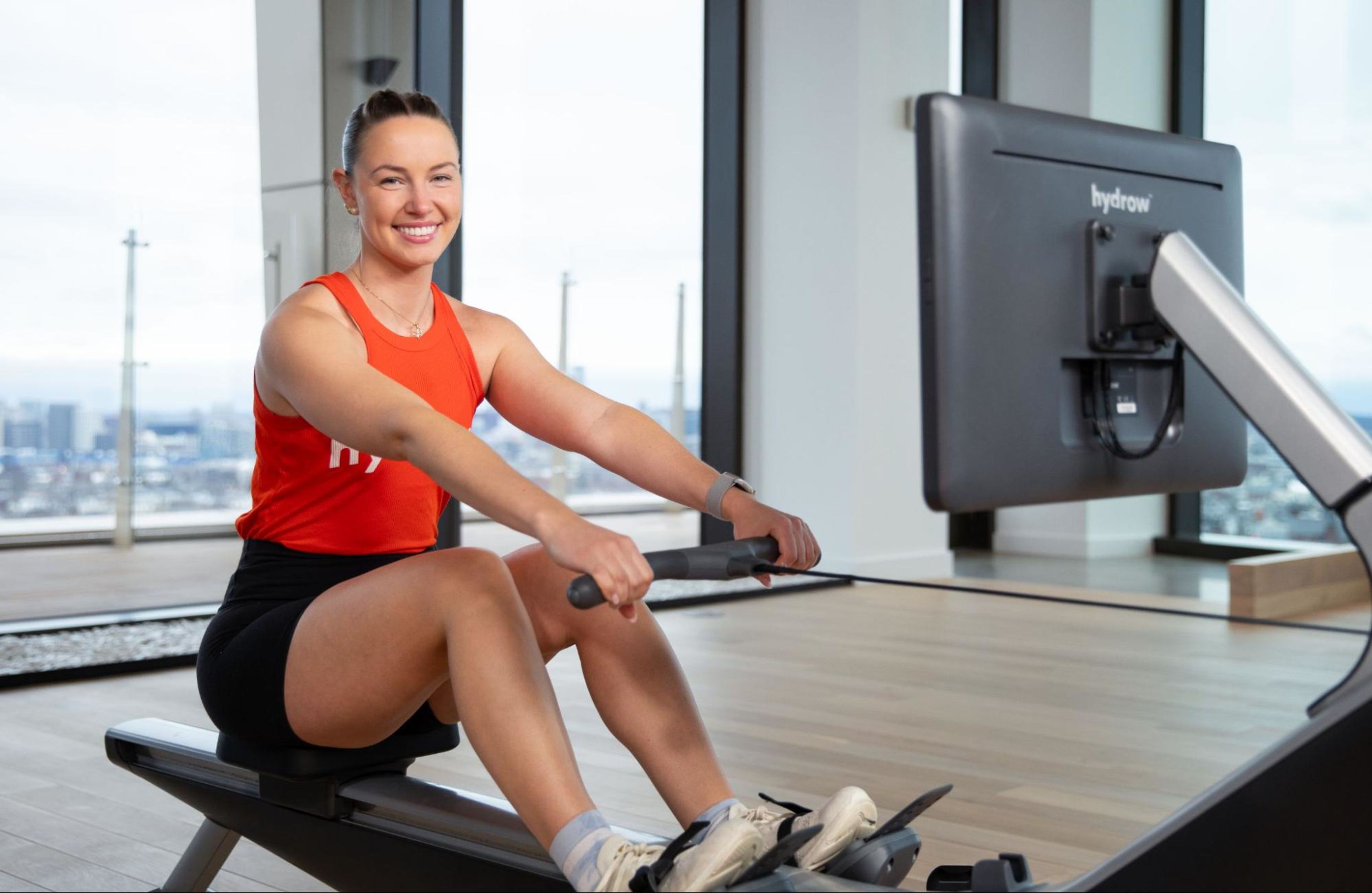 Hydrow Athlete Mac sits on a Hydrow rowing machine, which is one of the best rowing machines for beginners.