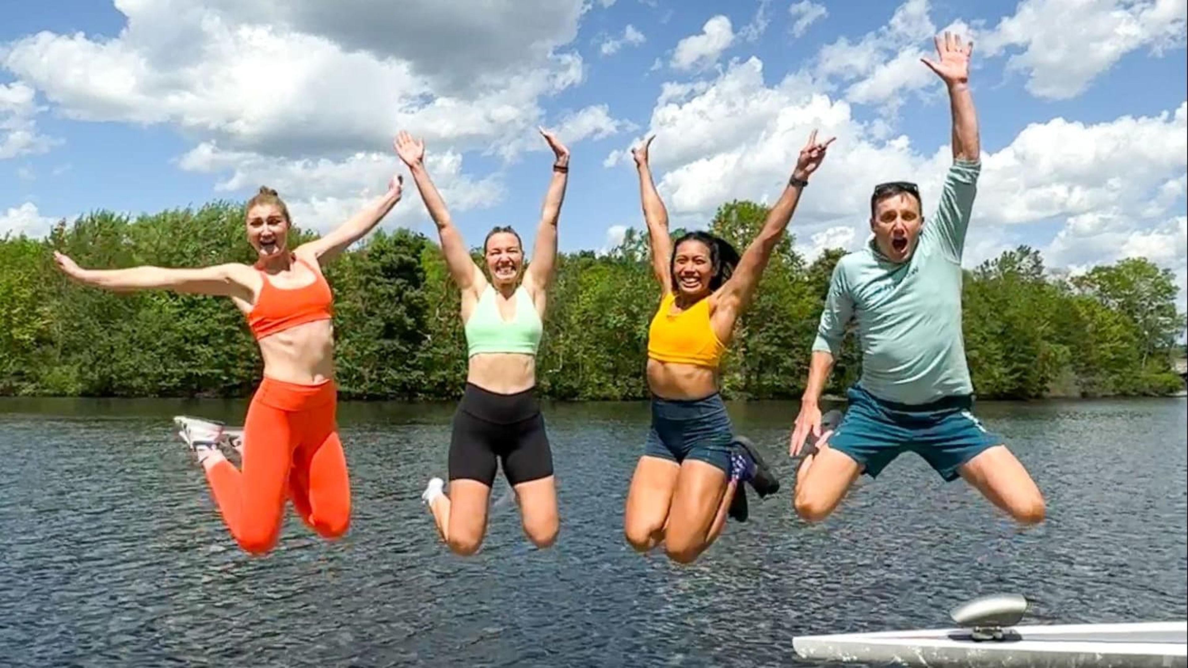 Hydrow Athlete jump on a dock in the summertime.