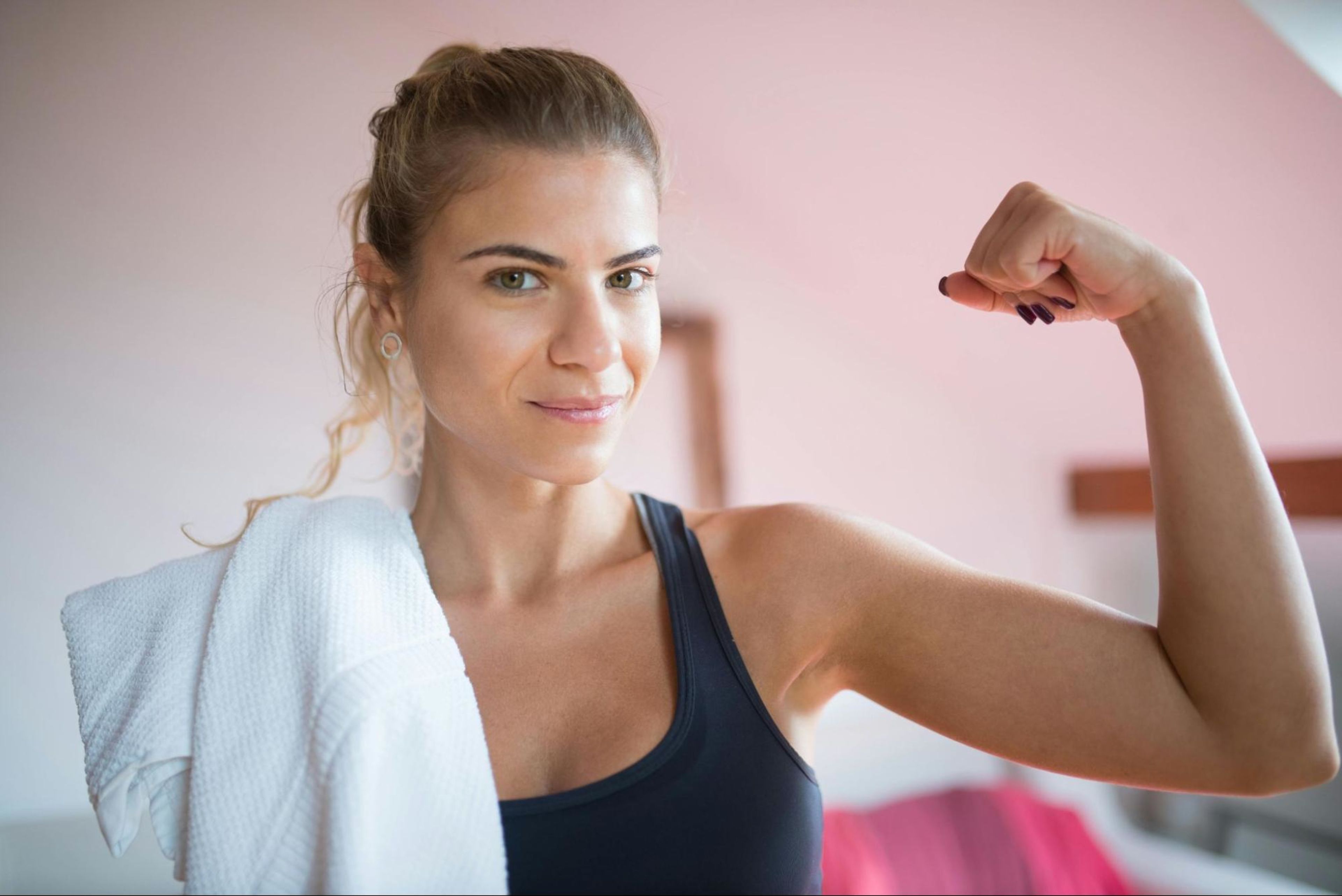 Woman flexes her arm muscle after doing the best arm workouts for women.