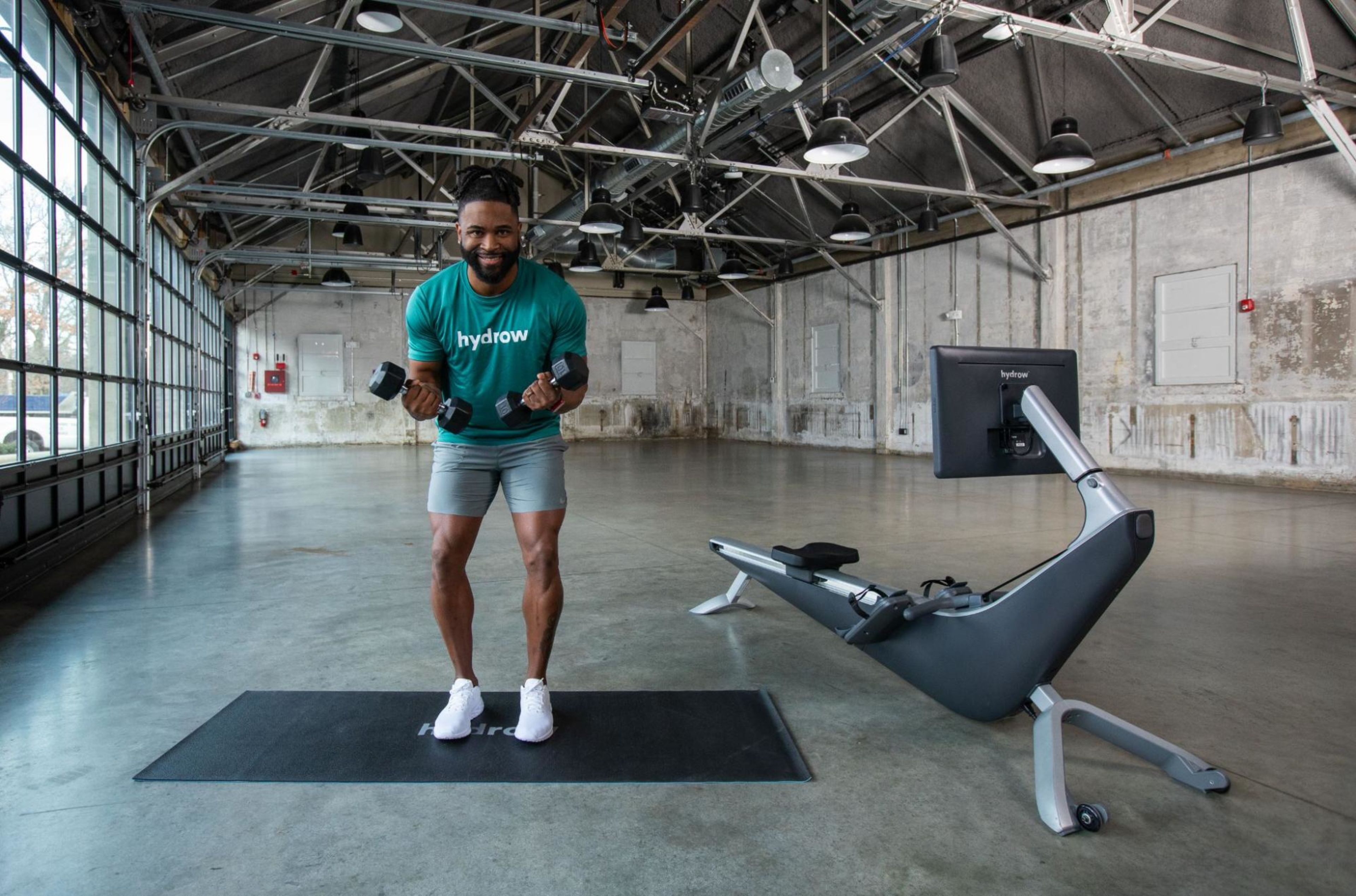 Hydrow Athlete Manteo demonstrates how to breathe when lifting weights with two dumbbells in his hands.