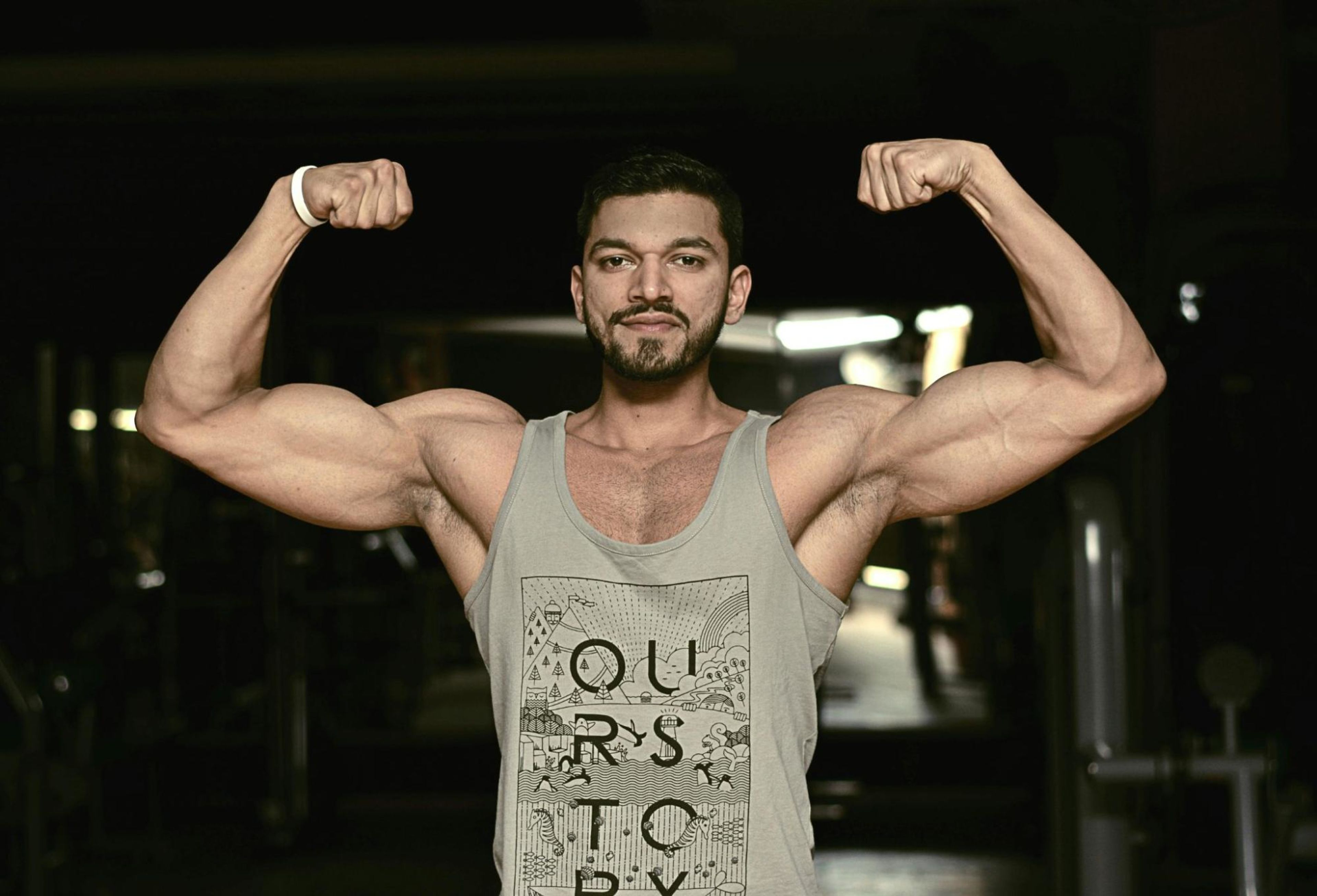 Man flexes his massive arm muscles after doing the best bicep workouts to build muscle and strength.
