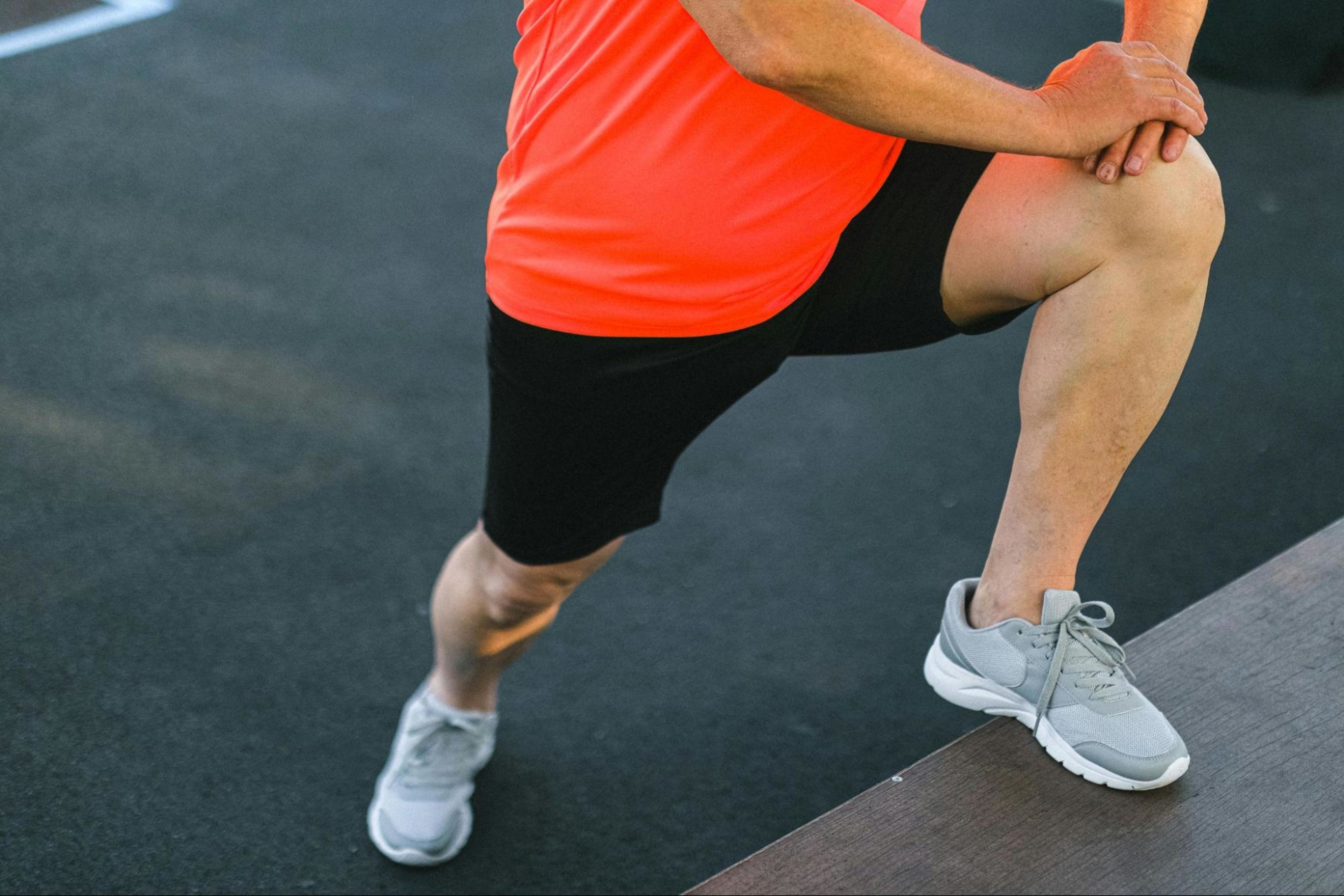 Man prepares to learn how to build leg muscle as he stretches his leg muscles outdoors.