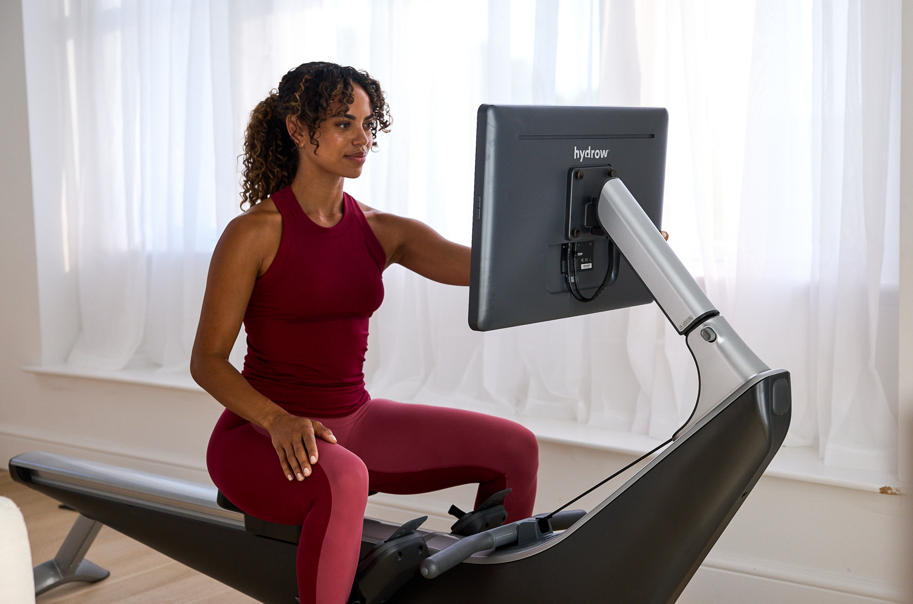 Woman prepares to work out on a Hydrow rowing machine.