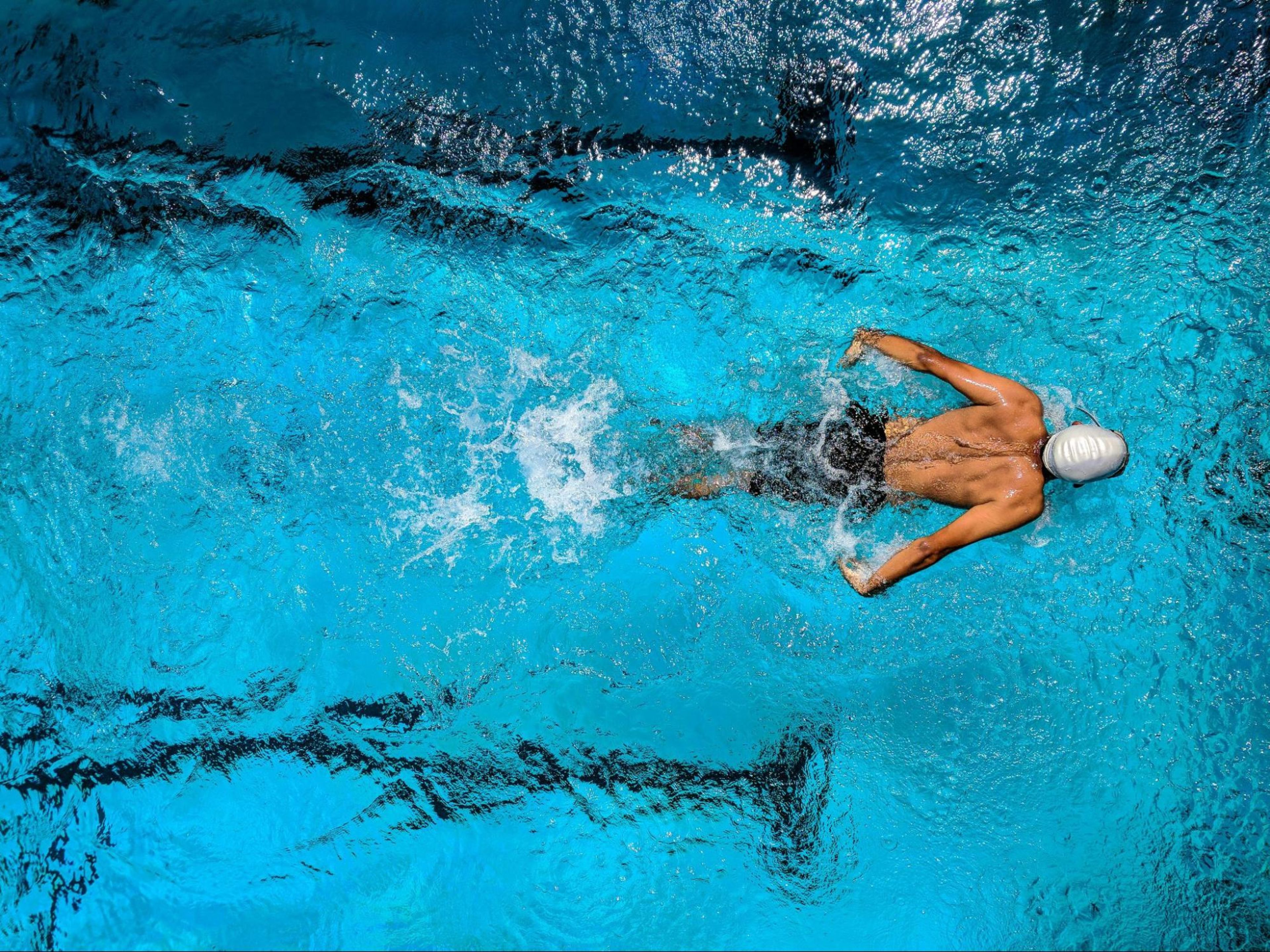 Man does a swimming workout after doing the best strength training exercises for swimmers.