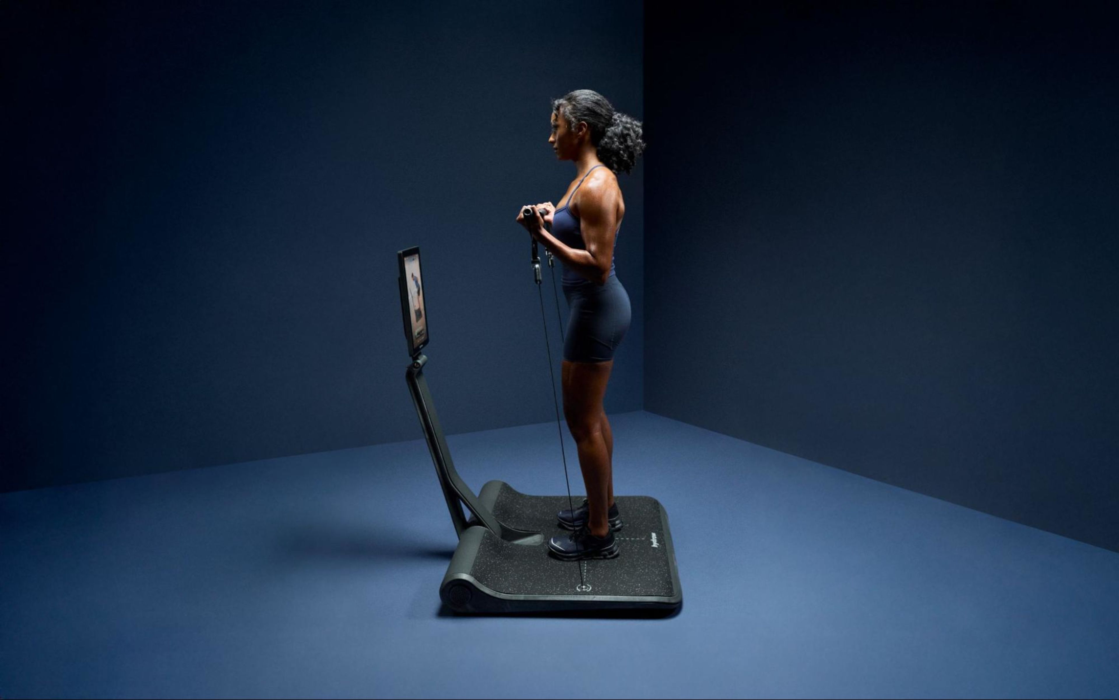 A woman does a workout on a LYQUID strength machine.