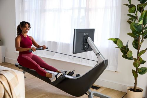 Woman works out on a rowing machine after learning whether low-impact workouts are effective.