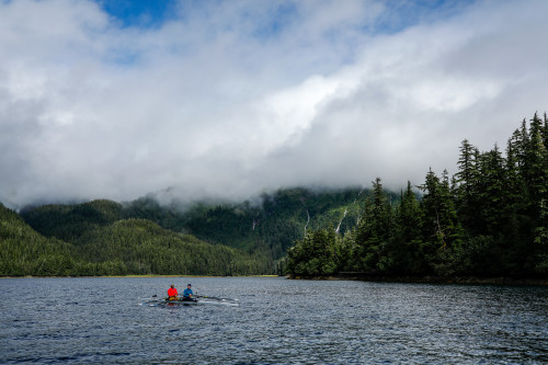 Two people rowing outdoors on a lake in the mountains