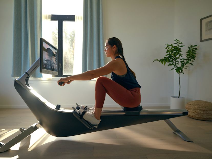 Woman burns calories while working out on her Hydrow rowing machine at home.