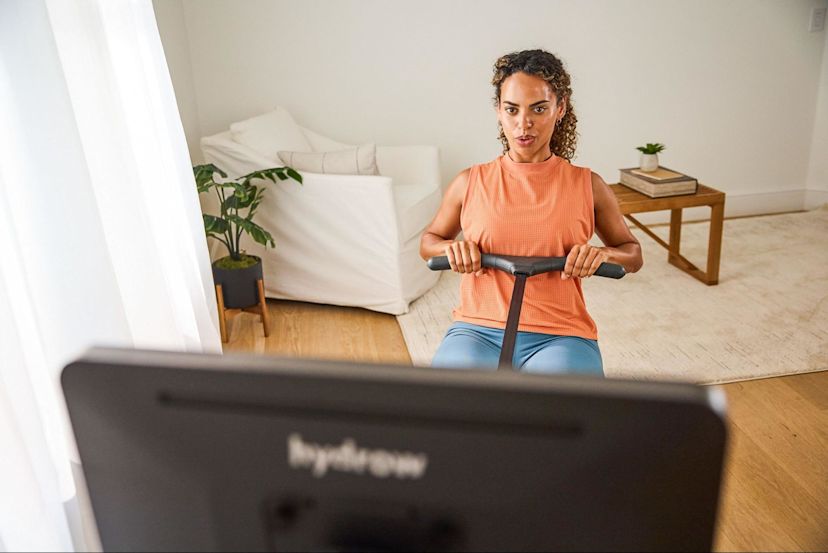 Woman works out on a rowing machine after asking "Is rowing cardio or strength?"