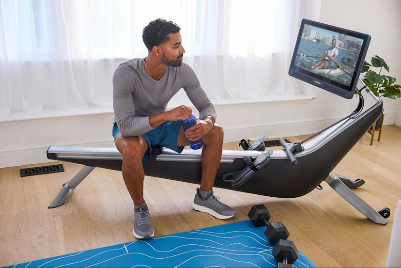 Man prepares to row on a Hydrow rowing machine after comparing the Hydrow Pro vs. Echelon.