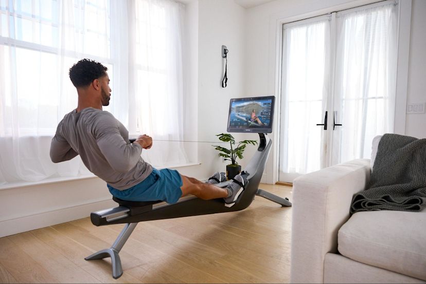 Man does a rowing machine workout in his living room on a Hydrow Pro rowing machine.