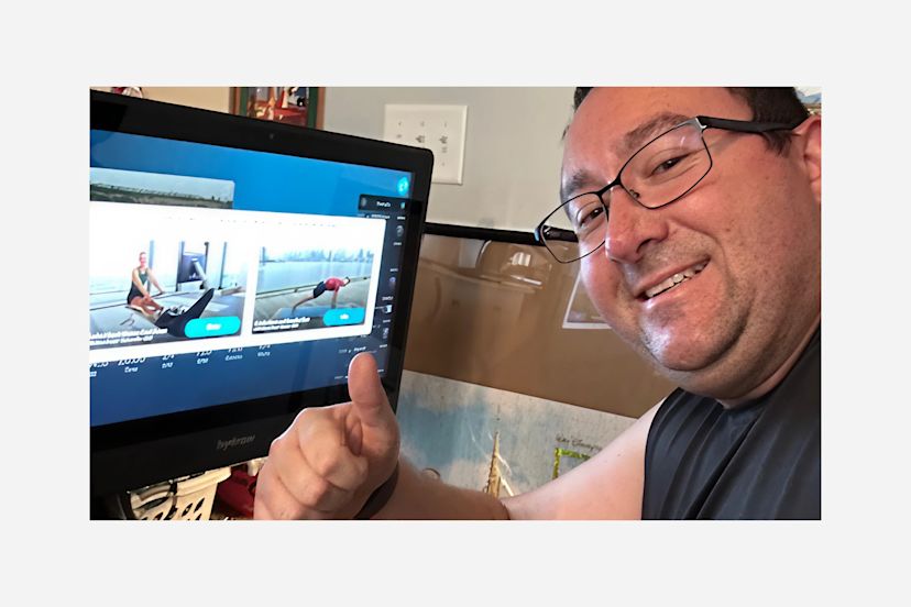 Hydrow Member Michael Sullivan poses in front of his rowing machine.