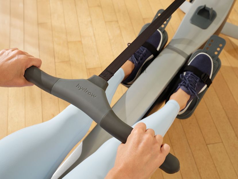 Woman rows using a handle on a Hydrow Arc rowing machine.
