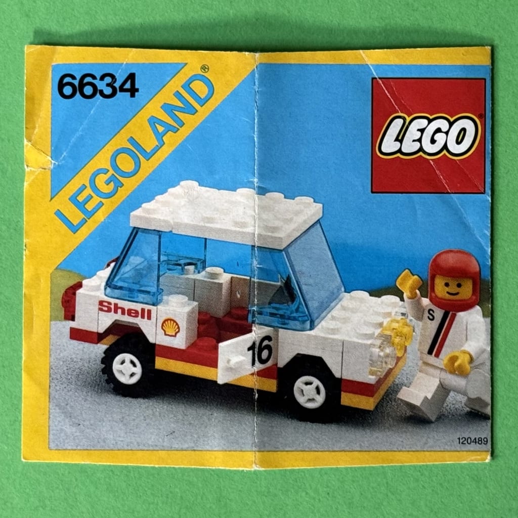 LEGO instruction booklet cover depicting a white, forward-tilting stock racing car with Shell advertisements and the driver next to the car wearing a red helmet
