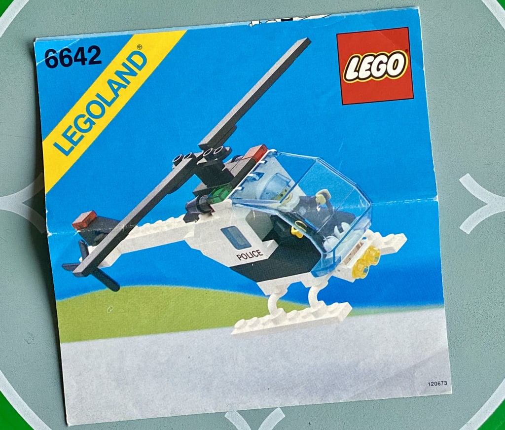 LEGO instruction booklet cover depicting a police minifig piloting a small police helicopter