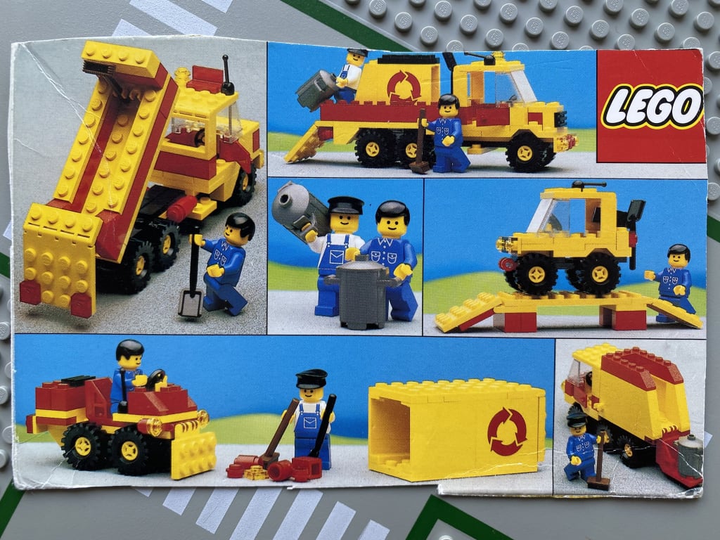 Two variants of flatbed trucks, a jeep on a ramp, a wheeled bulldozer, and a small refuse truck