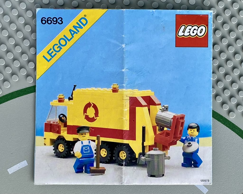 LEGO instruction booklet cover depicting a refuse collection truck and two minifigs in workwear emptying bins
