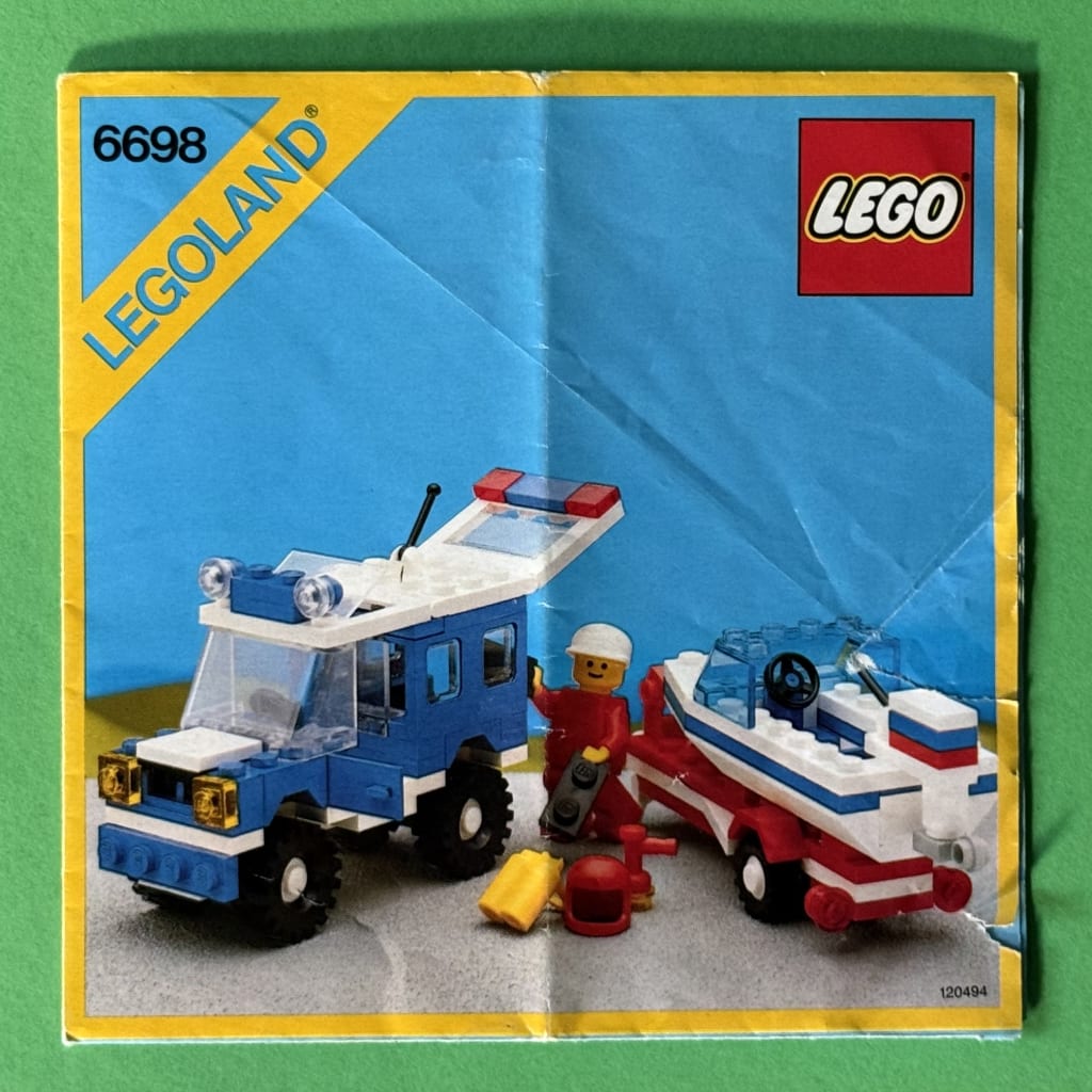 LEGO instruction booklet cover depicting a minifig loading diving equipment into the back of an RV, next to a boat on a trailer