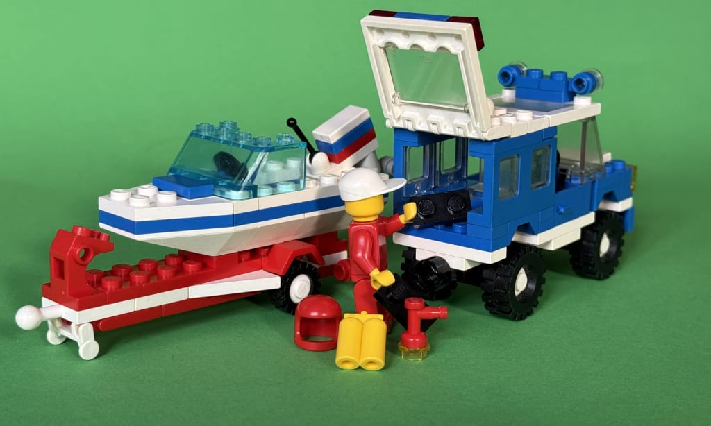 The minifigure packing equipment in the back of the vehicle, next to the detached trailer carrying the speedboat