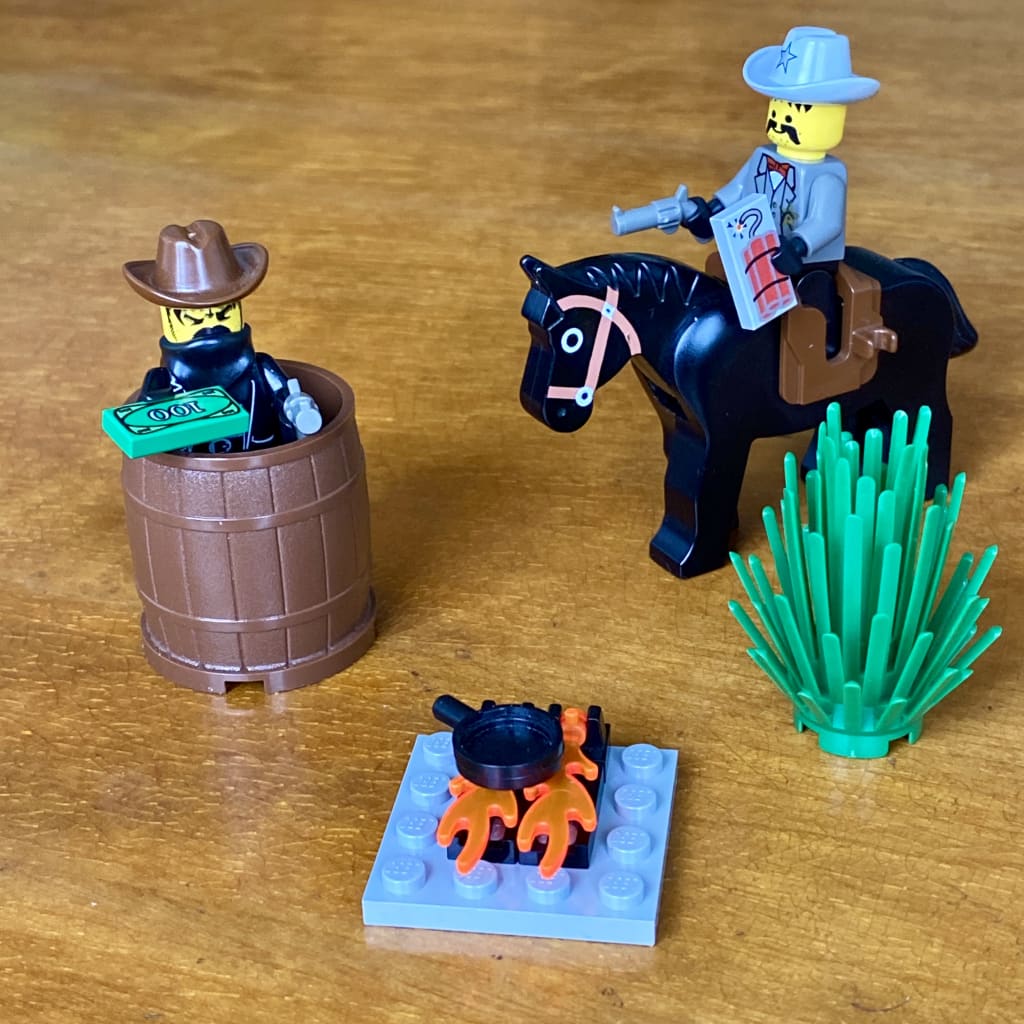 LEGO western bandit hiding in a barrel as a sheriff on a horse rides up to a camp fire