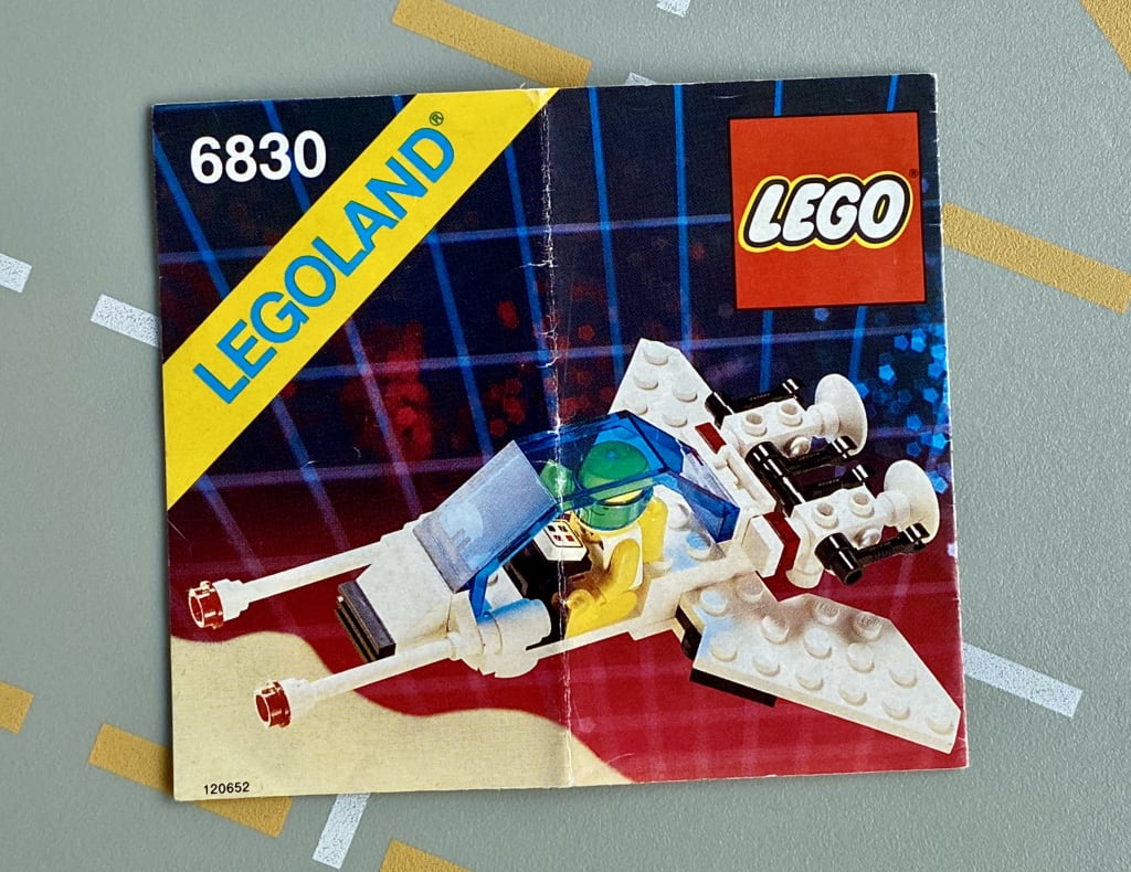 LEGO instruction booklet cover depicting a space minifig piloting a narrow spaceship with wings folded back