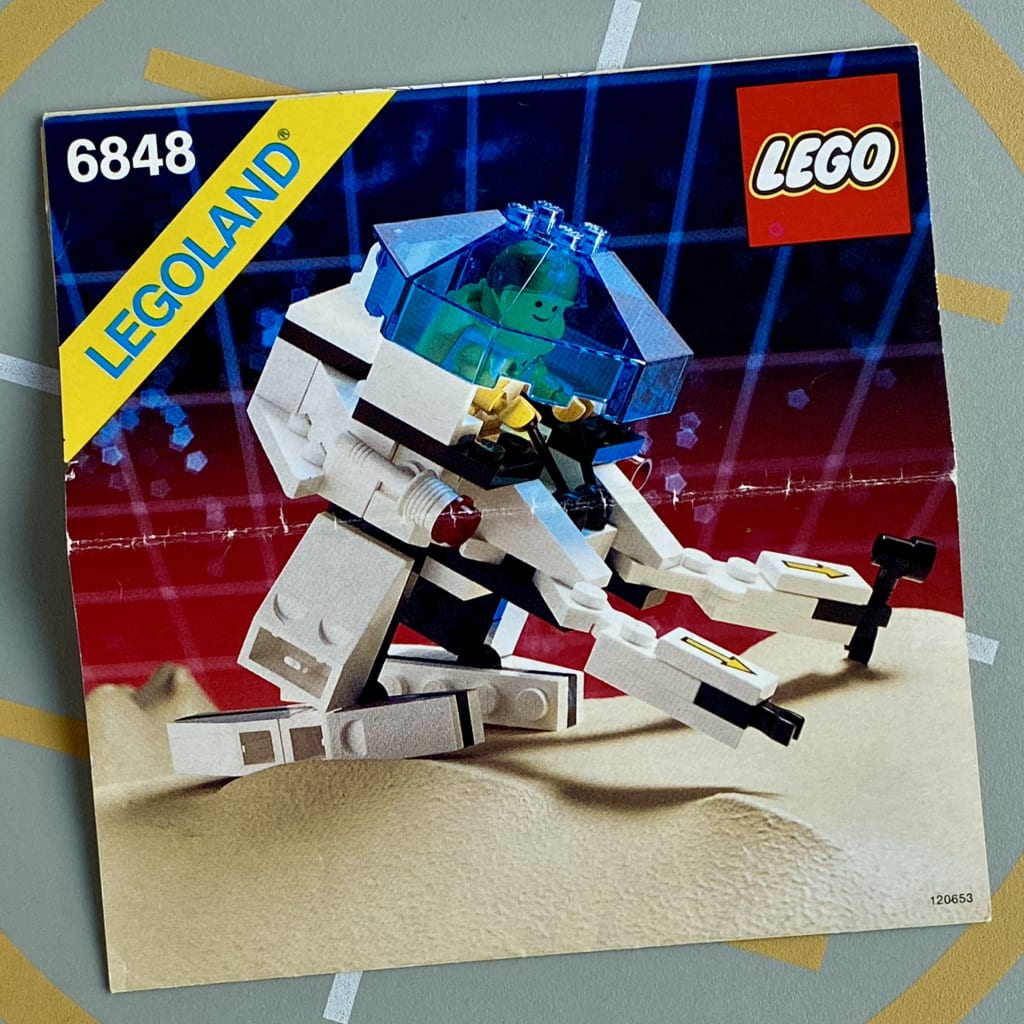 LEGO instruction booklet cover depicting a space minifig piloting a two-legged exploration vehicle with arms, holding tools
