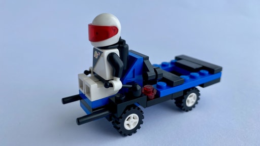 4-wheeled vehicle with seat in front, handles for steering and a flat back for loading a container