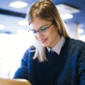 woman in glasses staring at digital device