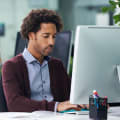 Person in plum sweater works at a desktop computer.